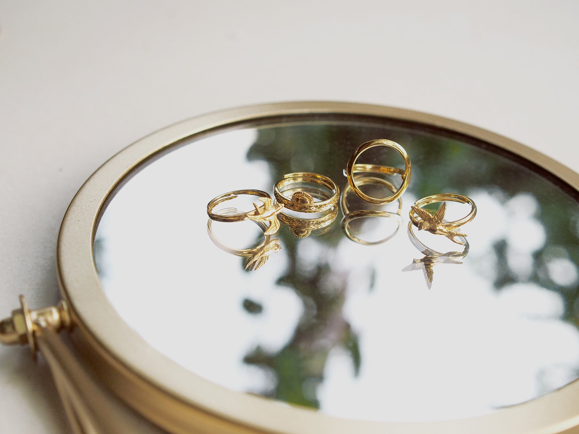 Close-up of a charming gold stacking ring set reflecting on a mirror