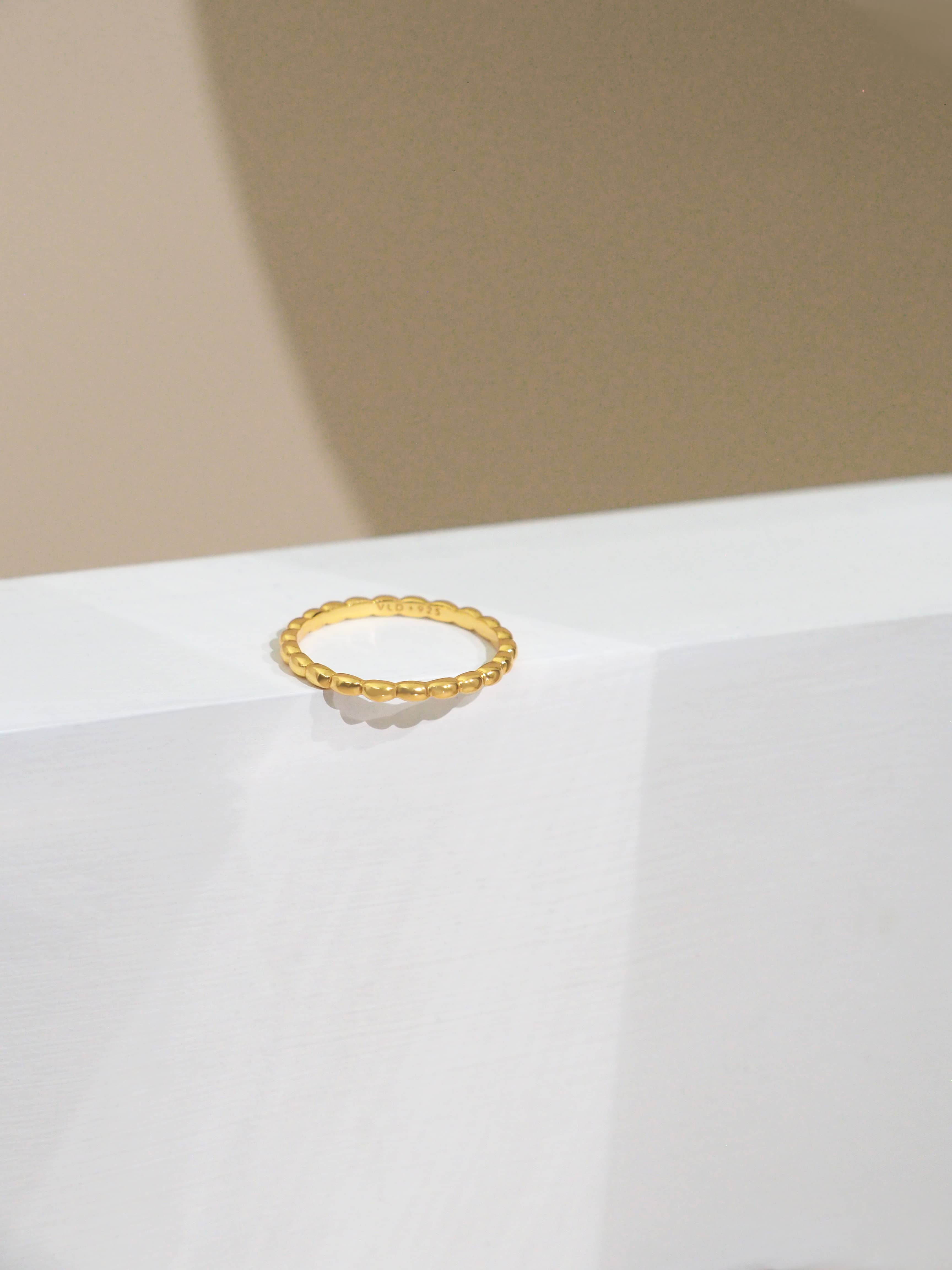 Modern, minimal gold-plated ring displayed on a clean background.