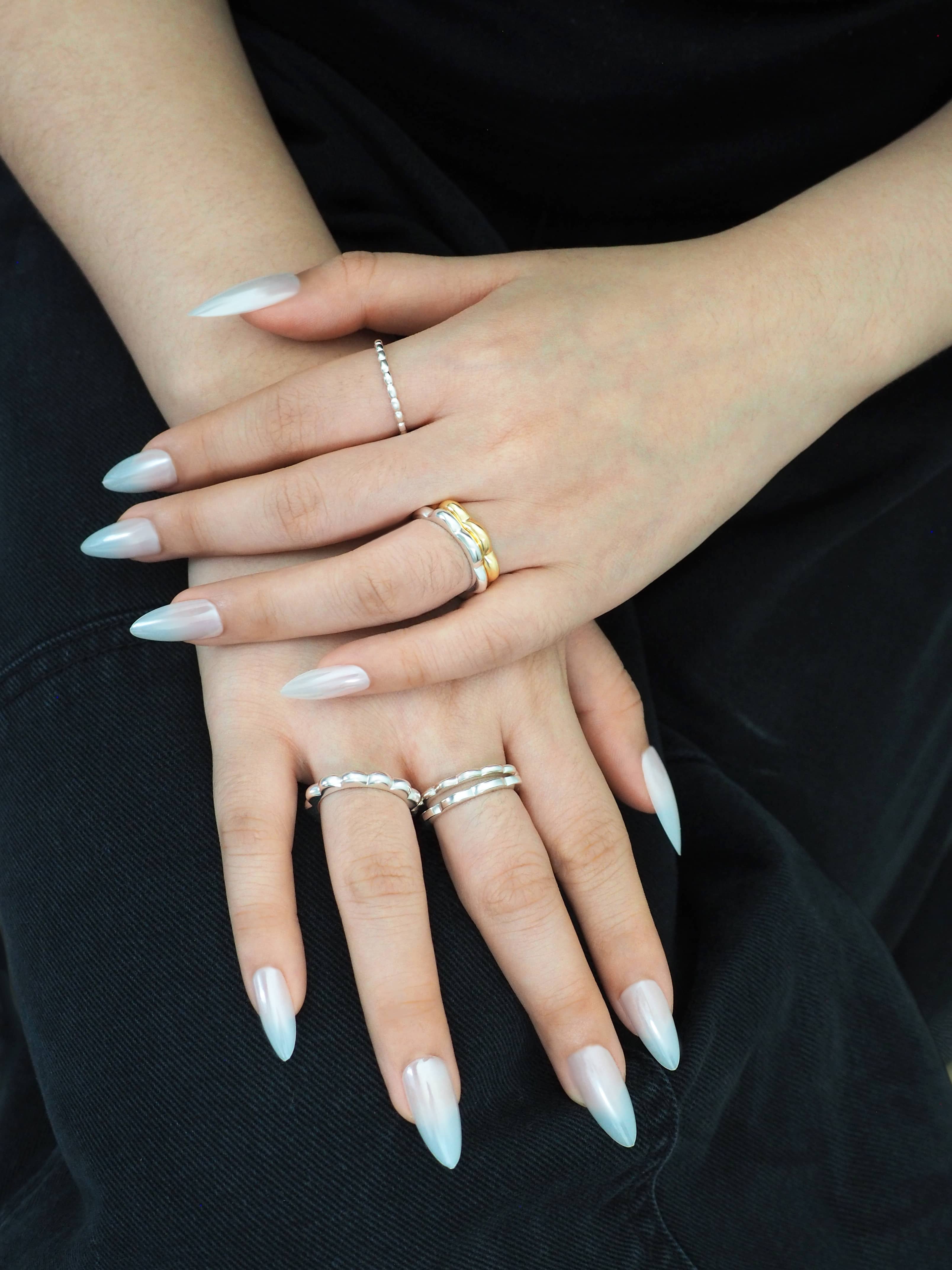 Close-up of hands wearing minimal gold and silver stacking rings