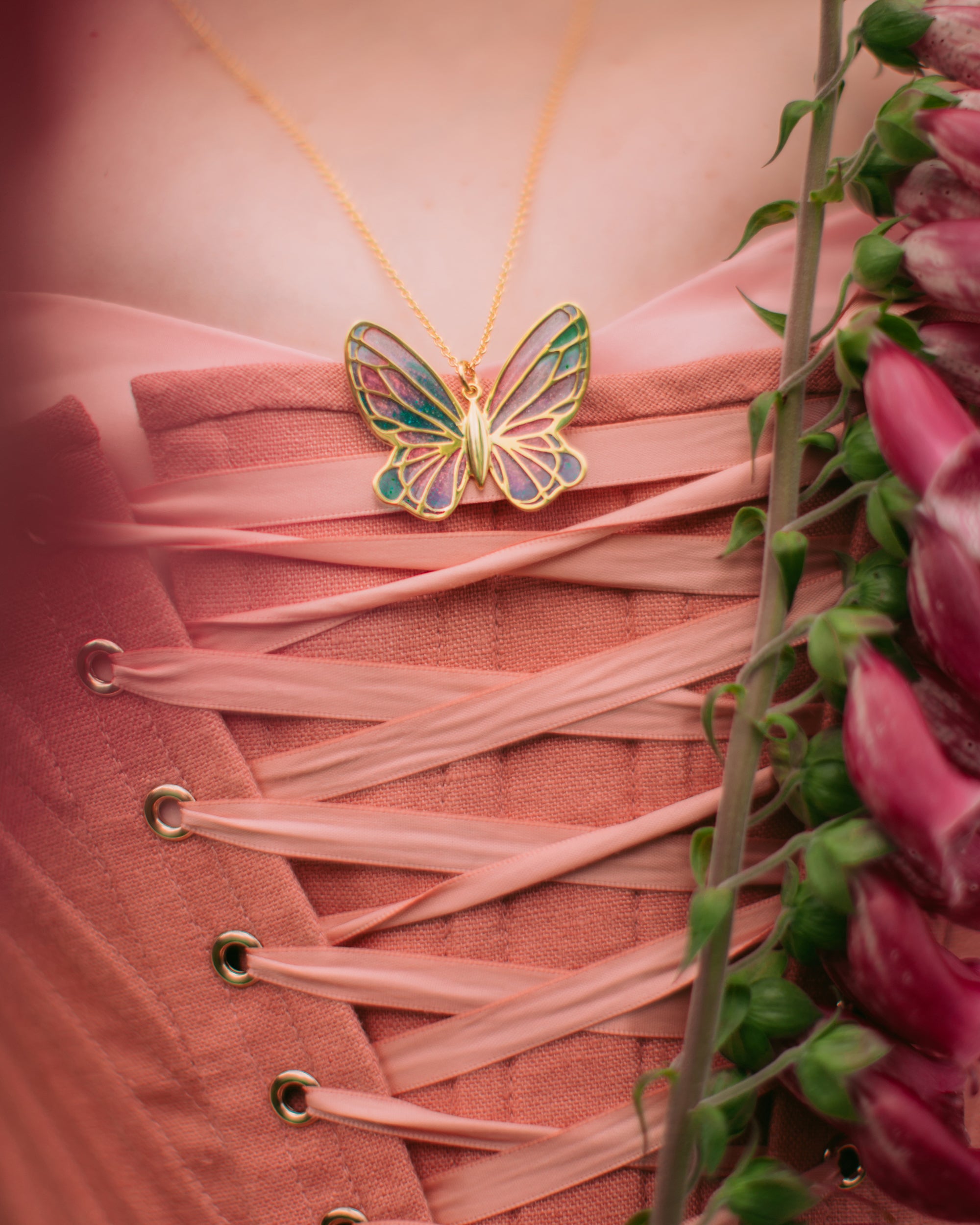 Close-up of a vibrant fairy butterfly pendant necklace on a pink dress.