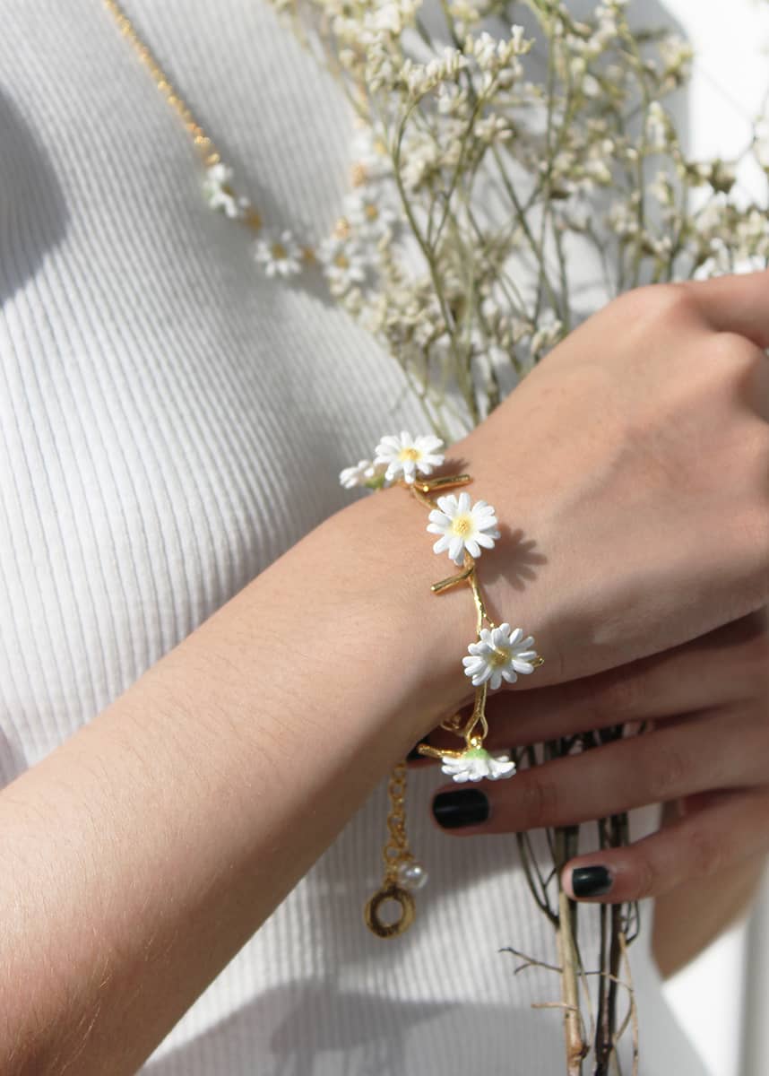 Close-up of a hand adorned with a floral bracelet holding dried flowers.