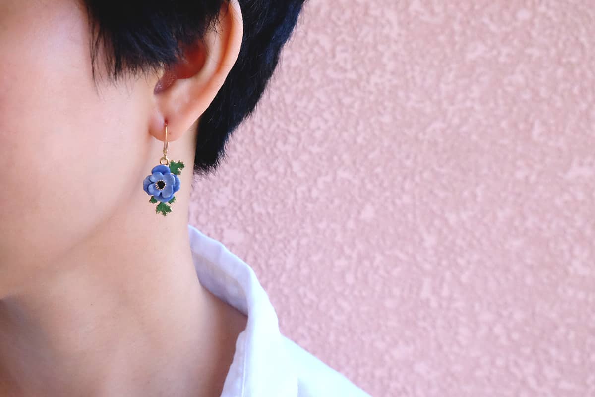A model wearing purple flower earrings.