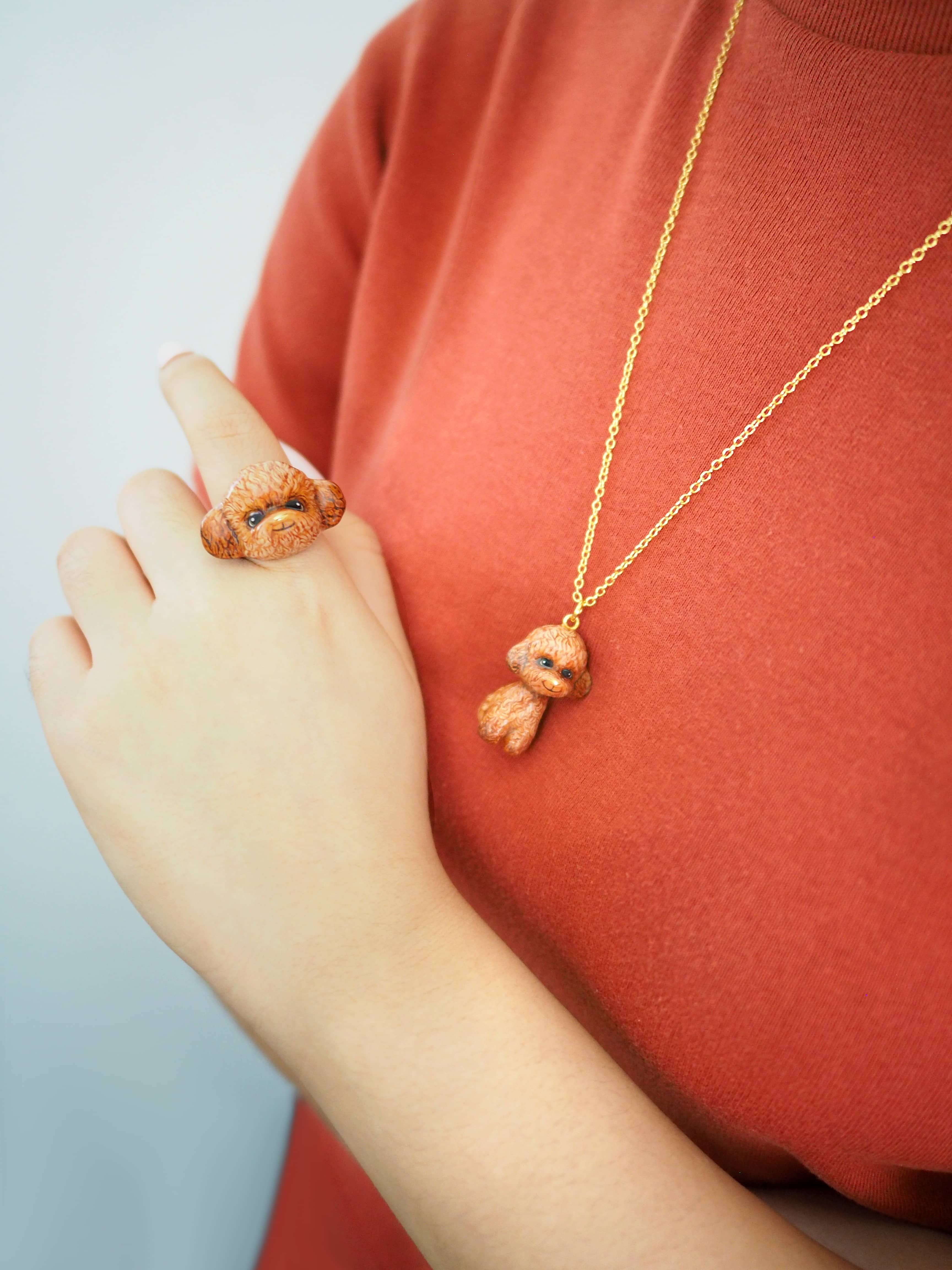 Close-up of a cute poodle ring and necklace displayed on a model.