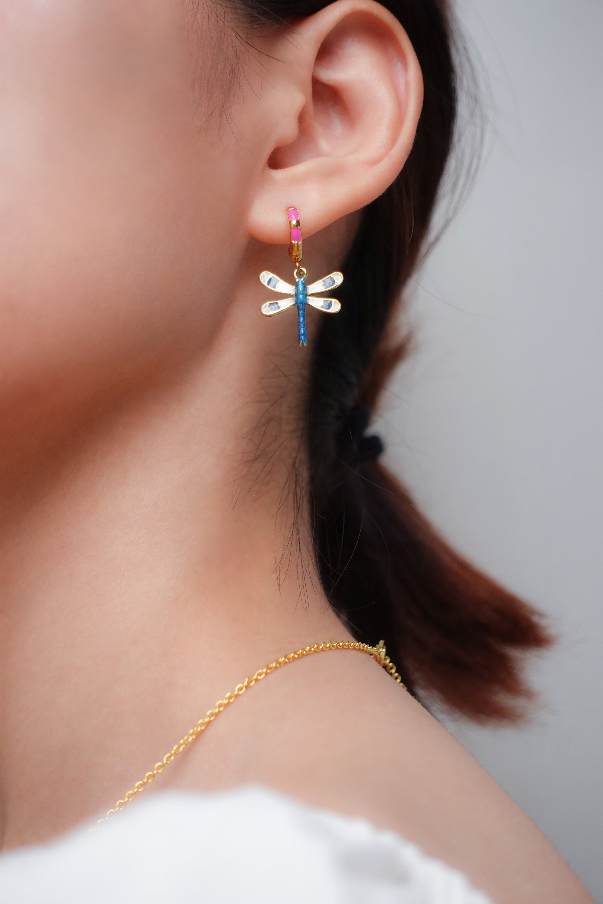 Close-up of a woman's ear showcasing beautiful dragonfly earrings.