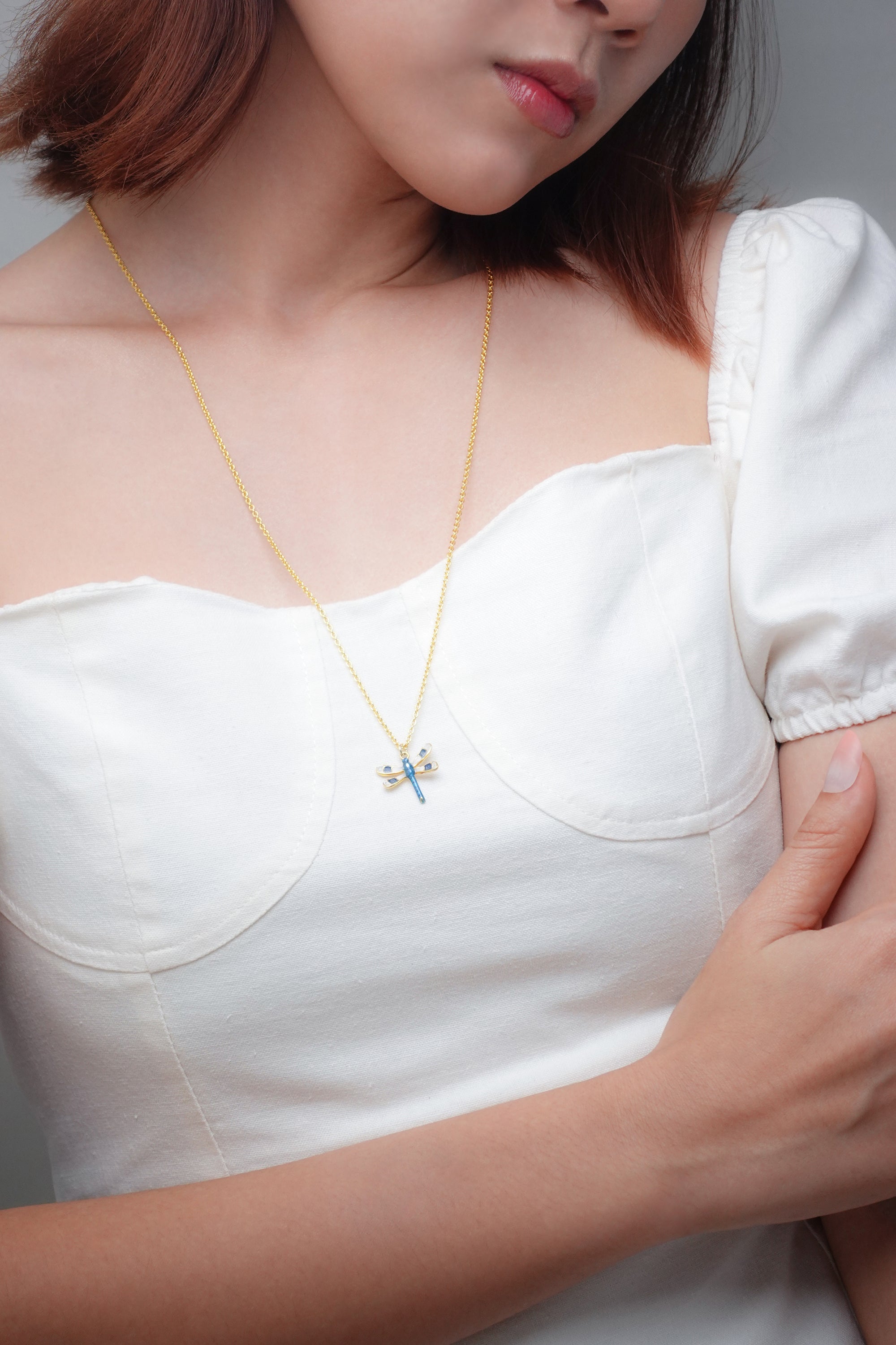 Close-up of stylish dragonfly necklace on a woman's neck.