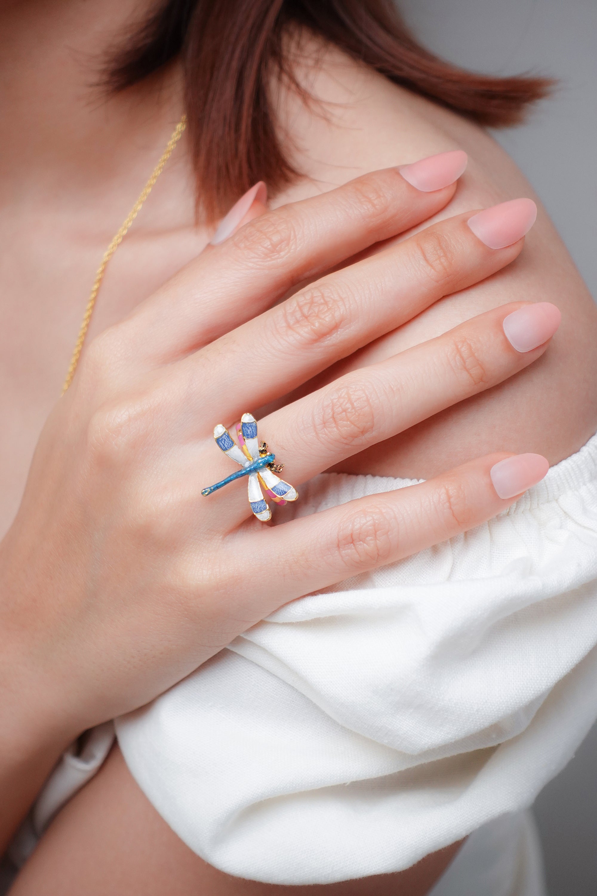 A close-up of a model's hand wearing a beautiful dragonfly ring.
