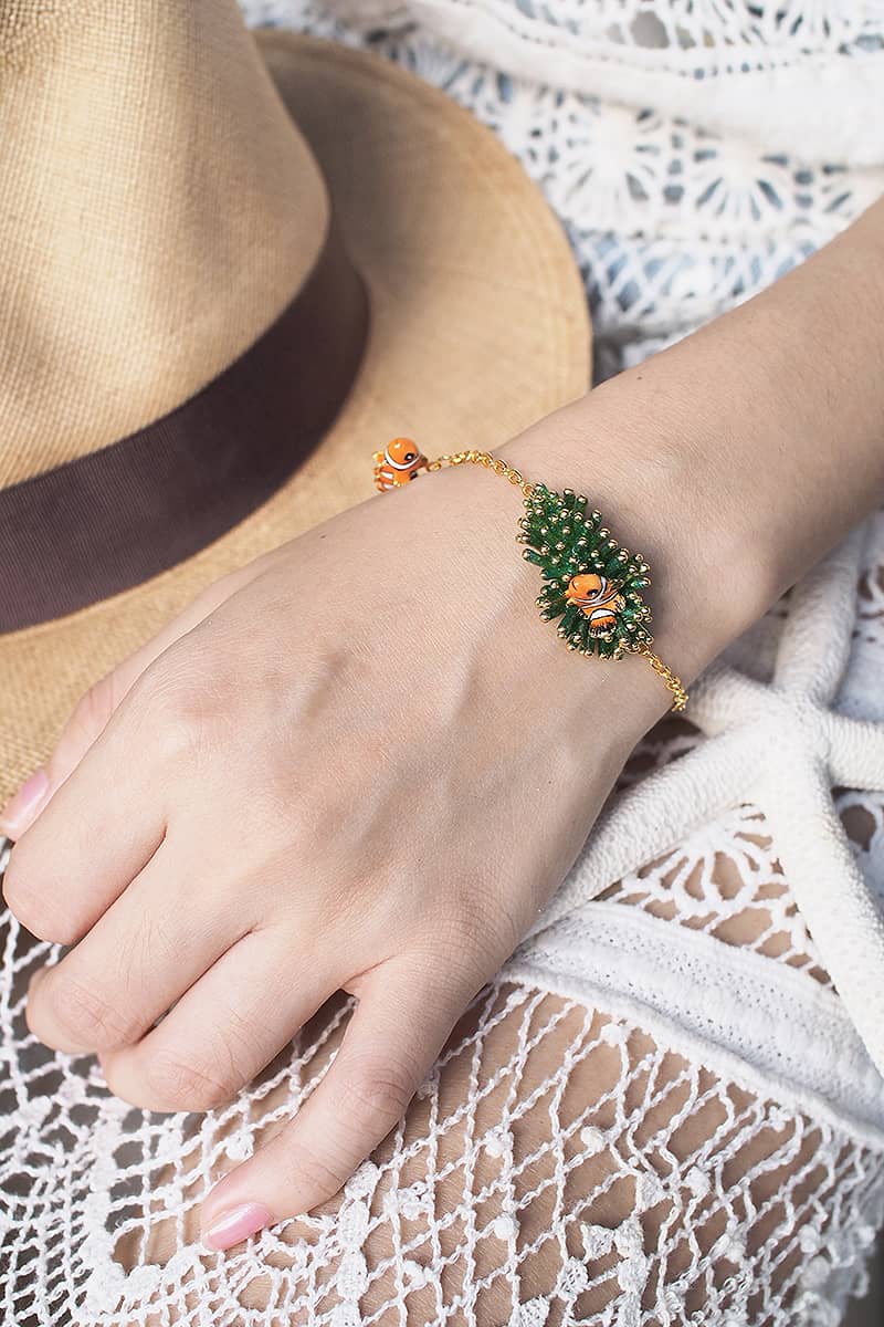 Handmade bracelet featuring clownfish and green coral on a woman's wrist, perfect for summer outfits.