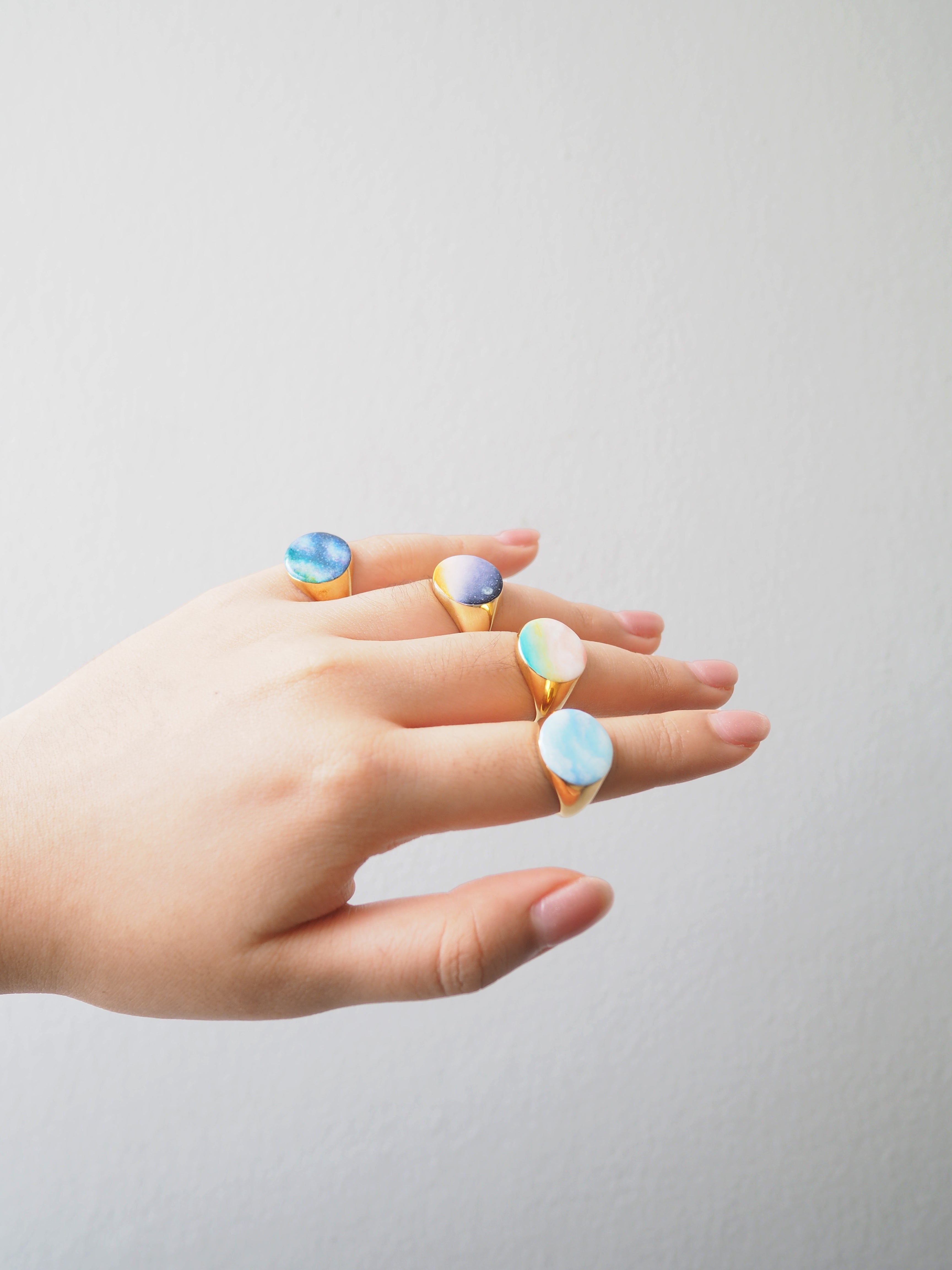 Collection of hand-painted ring featuring a sky design on a hand.
