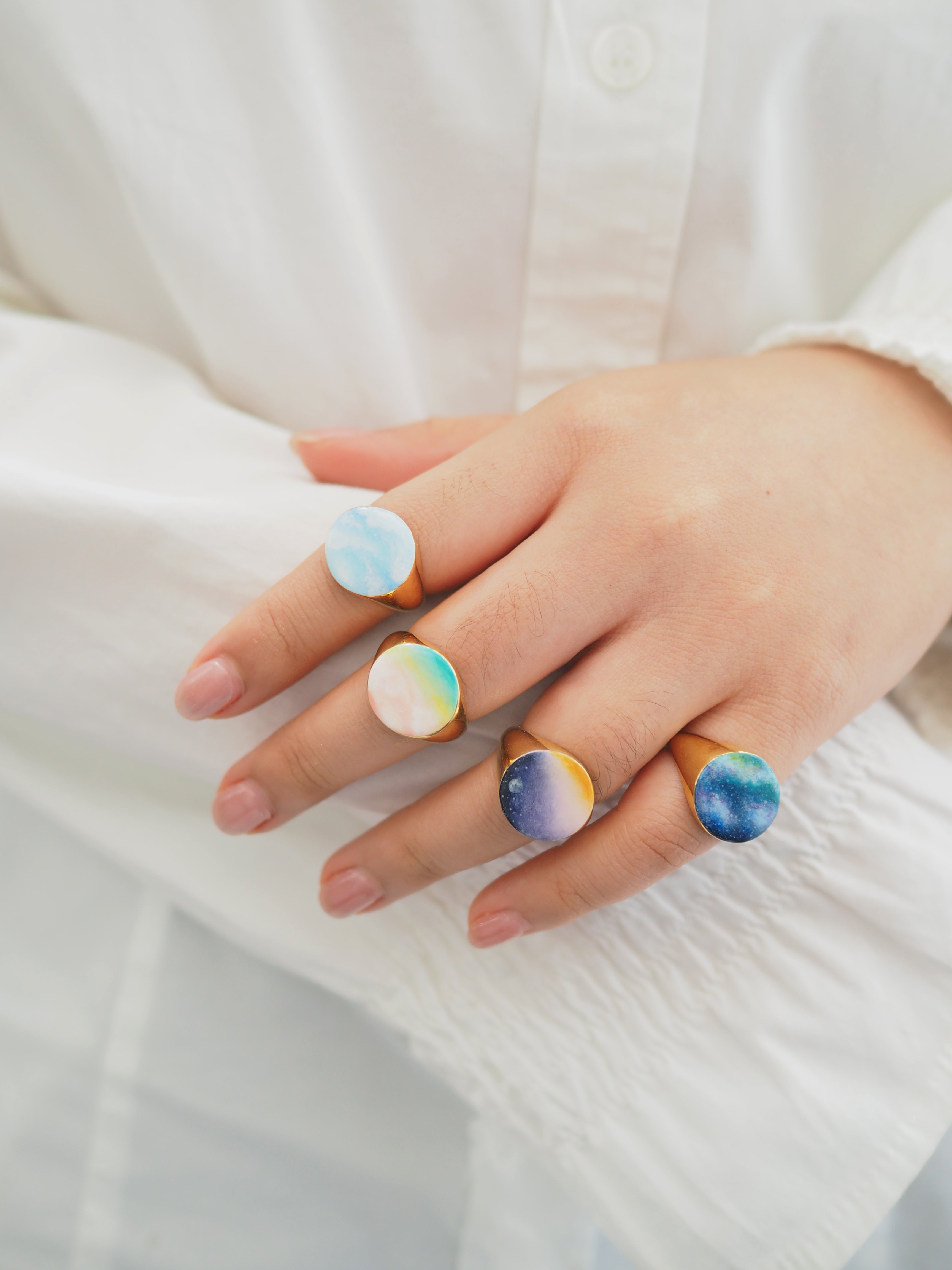 Collection of hand-painted ring featuring a sky design on a hand.