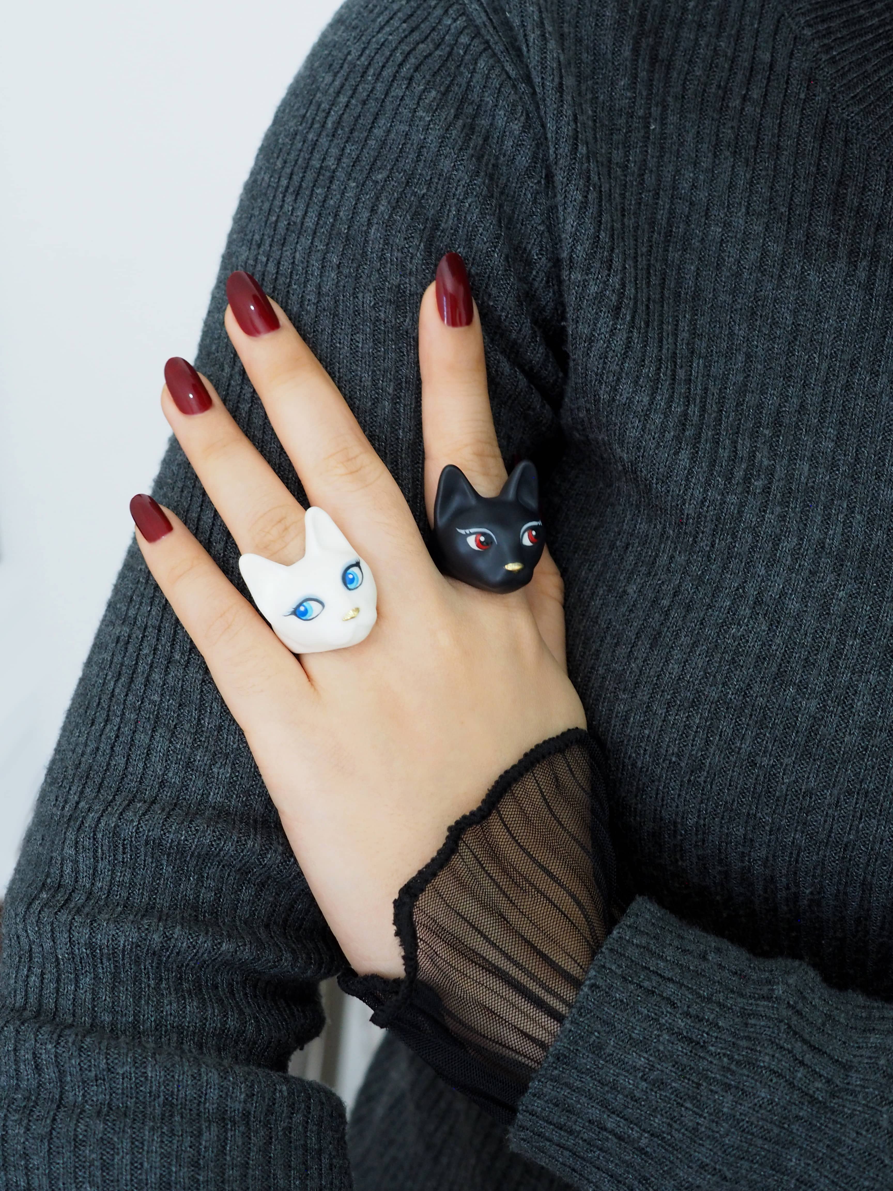 A woman wearing two cat ring in black and white with unique design, perfect for art collectors.