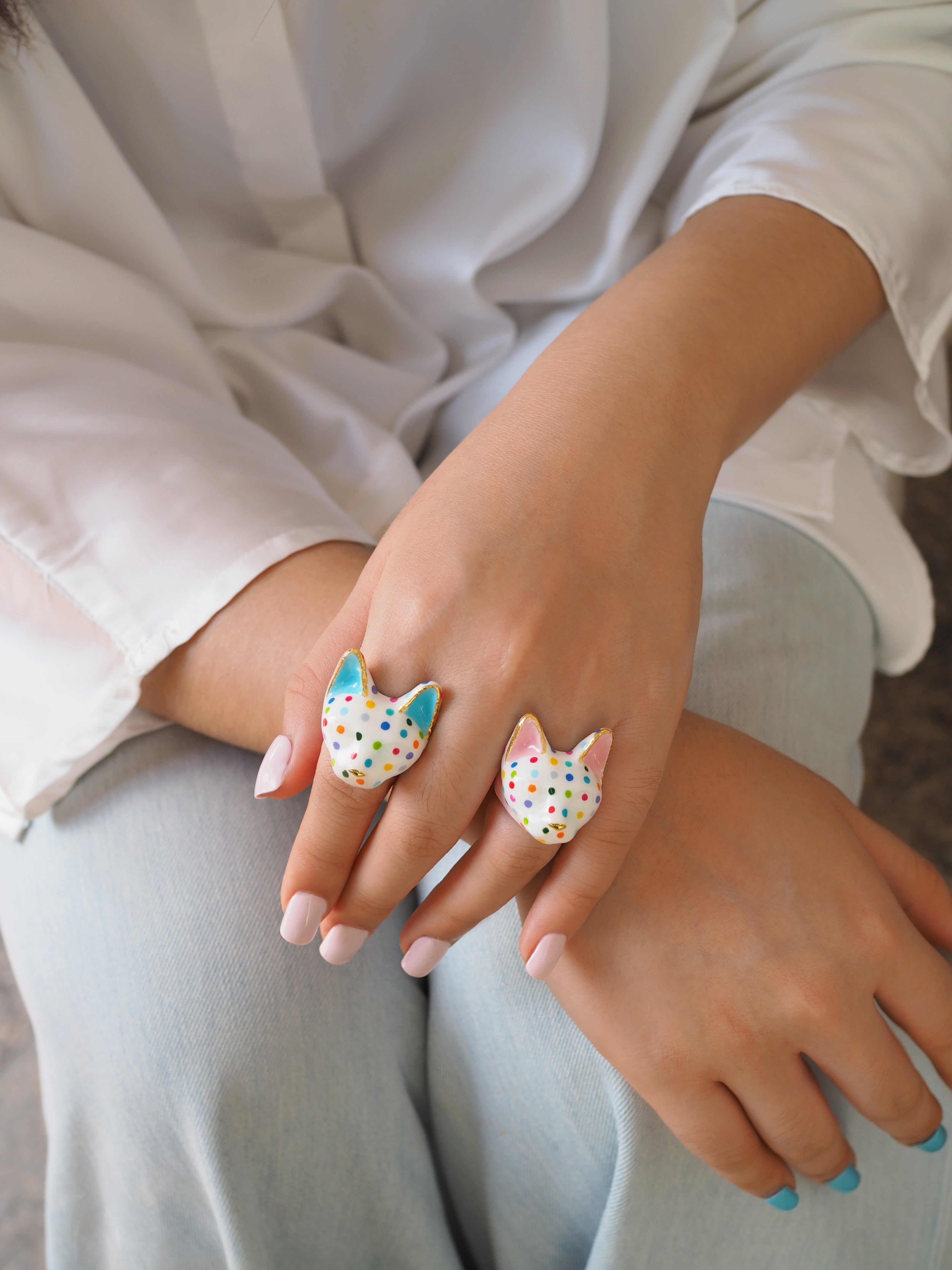 A hand adorned with two playful cat rings with polka dot.
