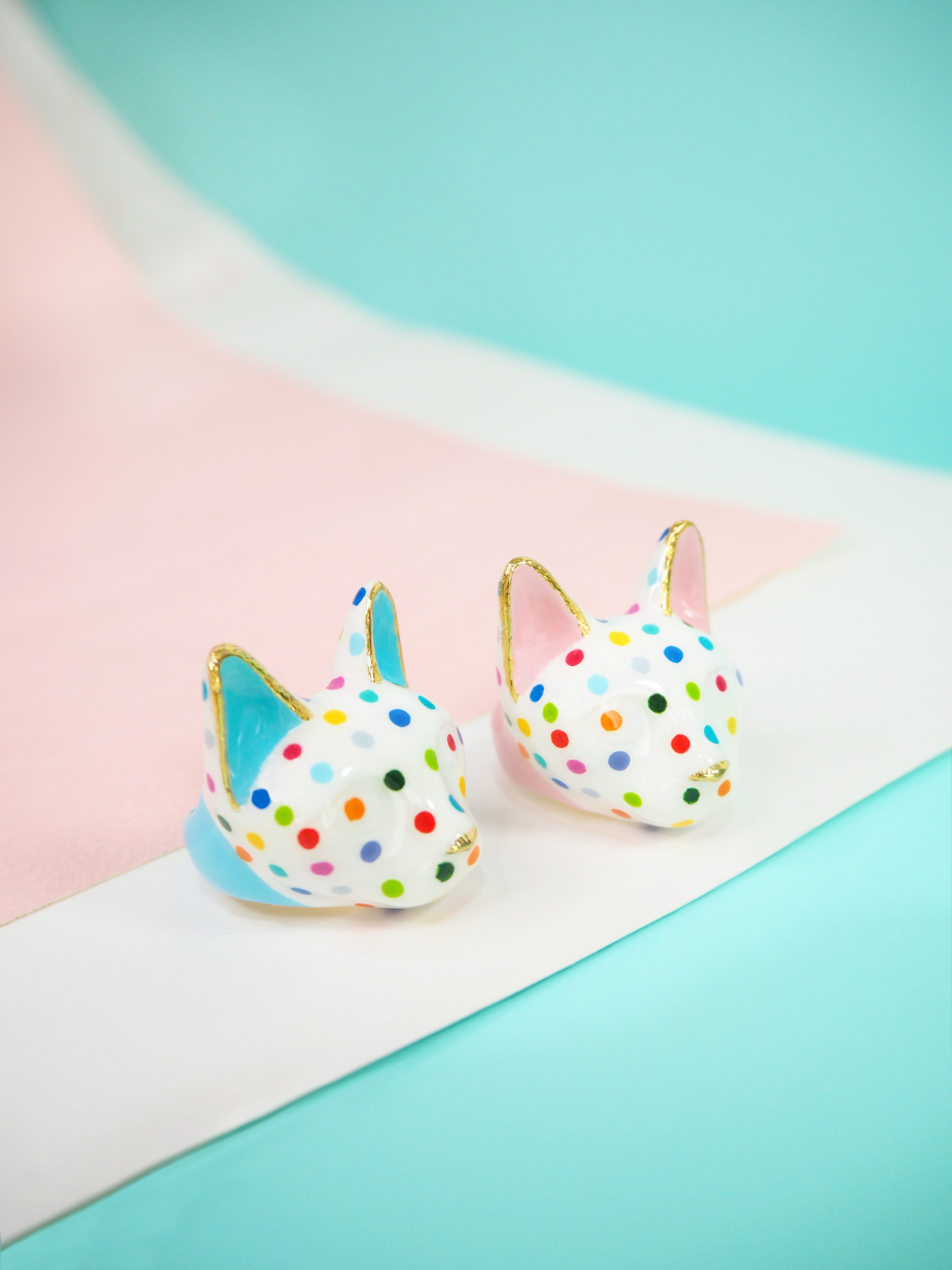 Two colorful cat rings with polka dots on a pastel background.
