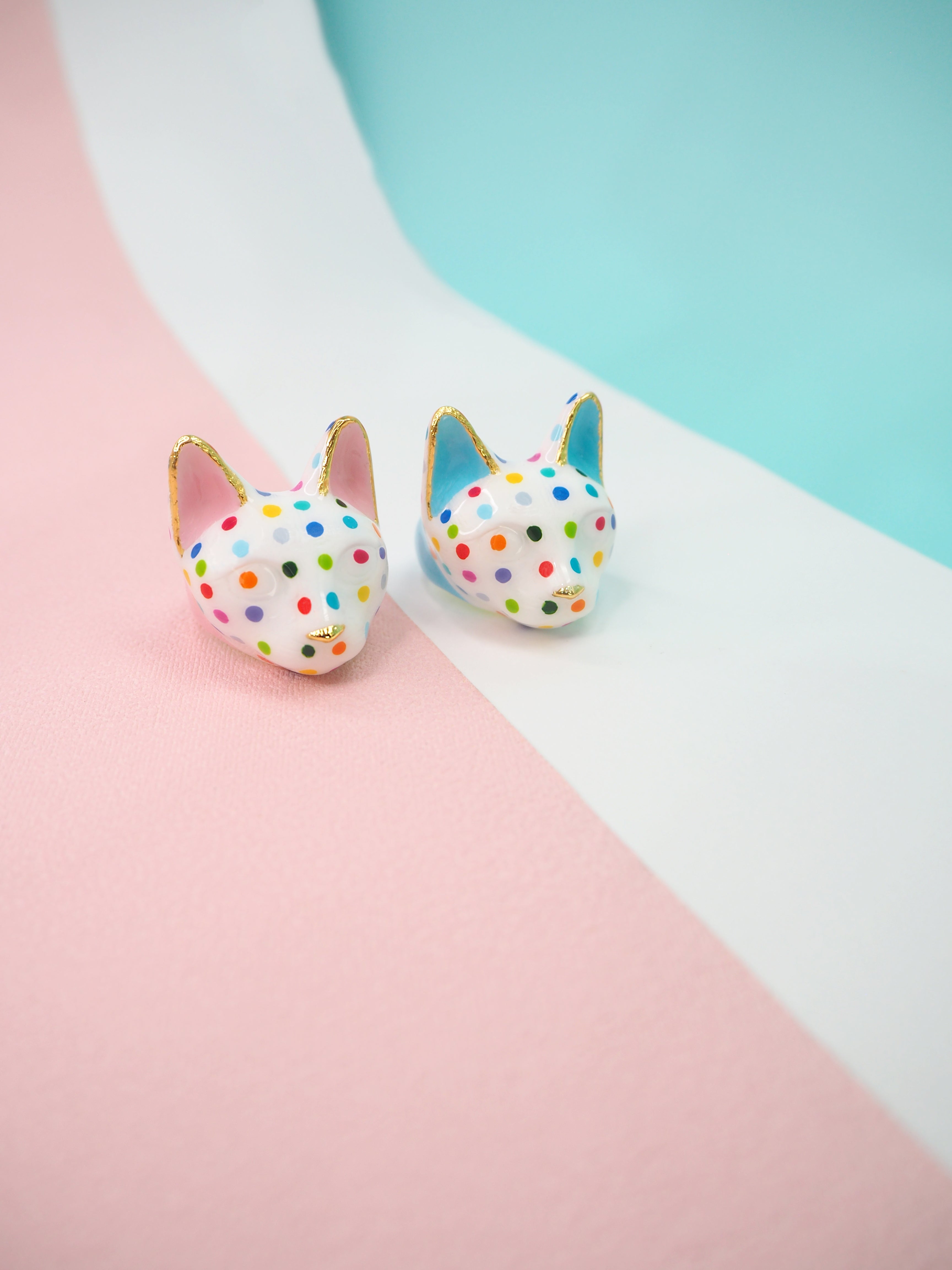 Two colorful cat rings with polka dots on a pastel background.