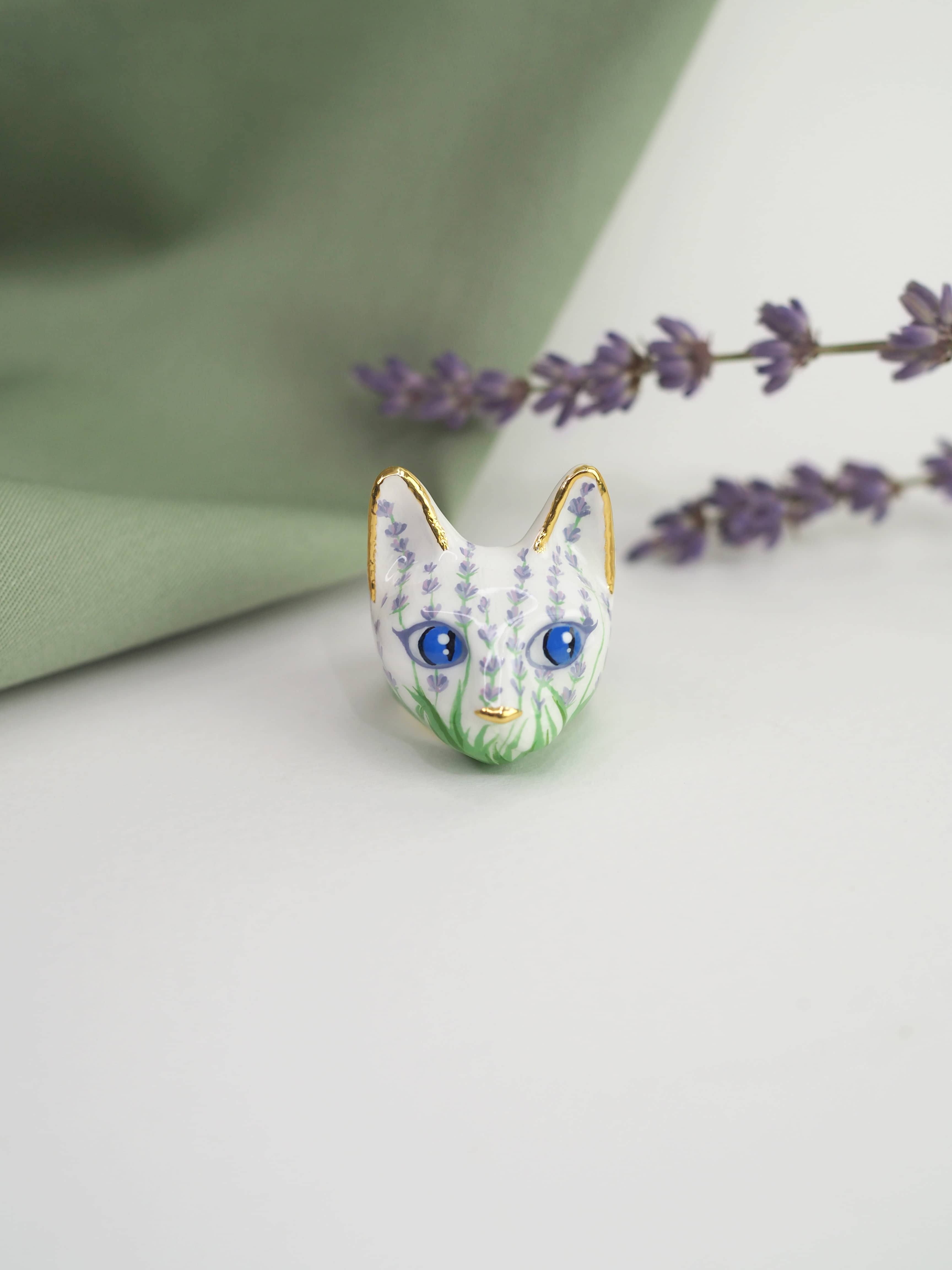 A beautiful cat rings with colorful floral patterns placed against a soft green background, alongside sprigs of lavender.