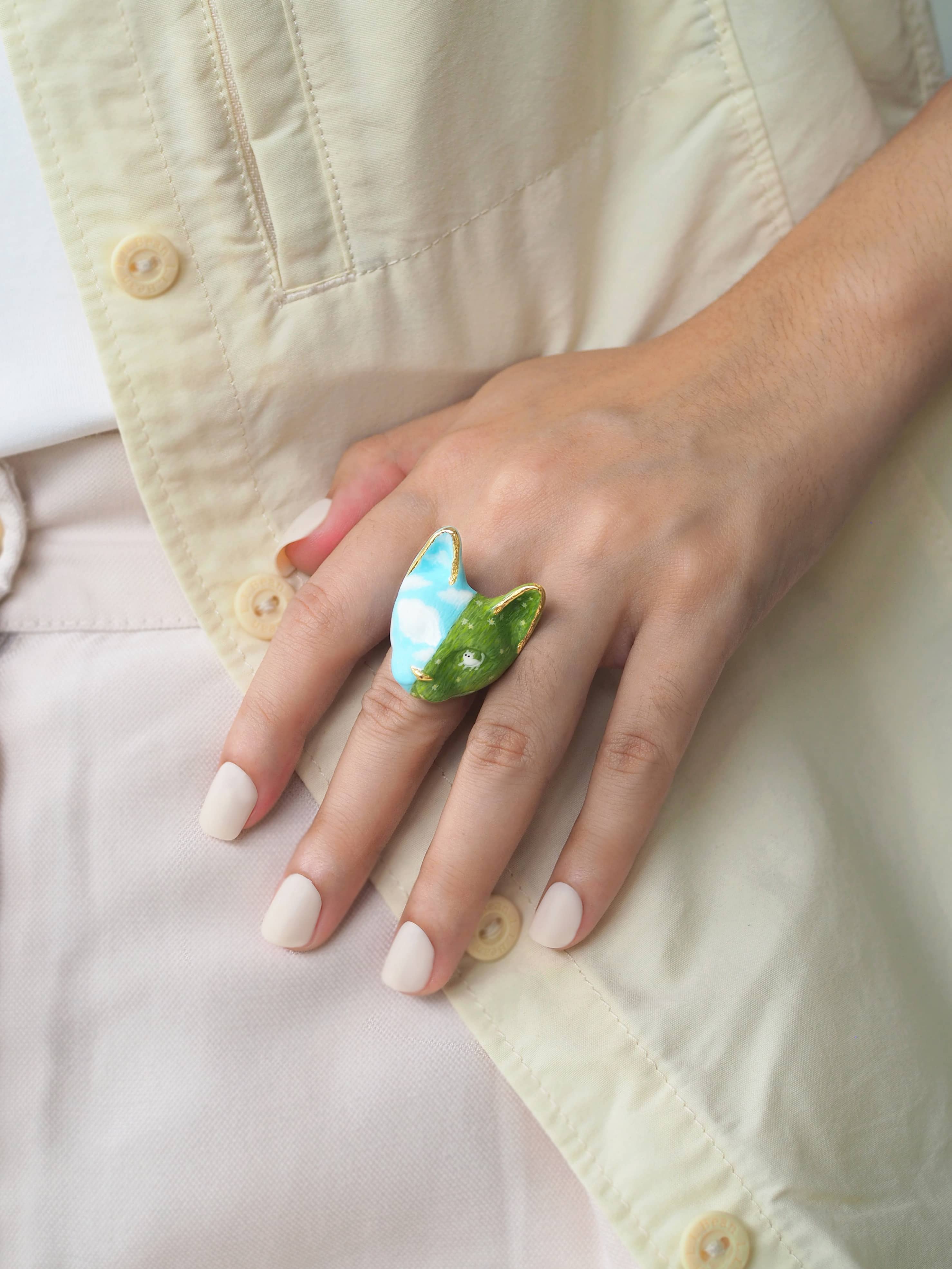A beautifully hand-painted cat ring featuring vibrant colors worn on a hand, perfect for cat lovers.