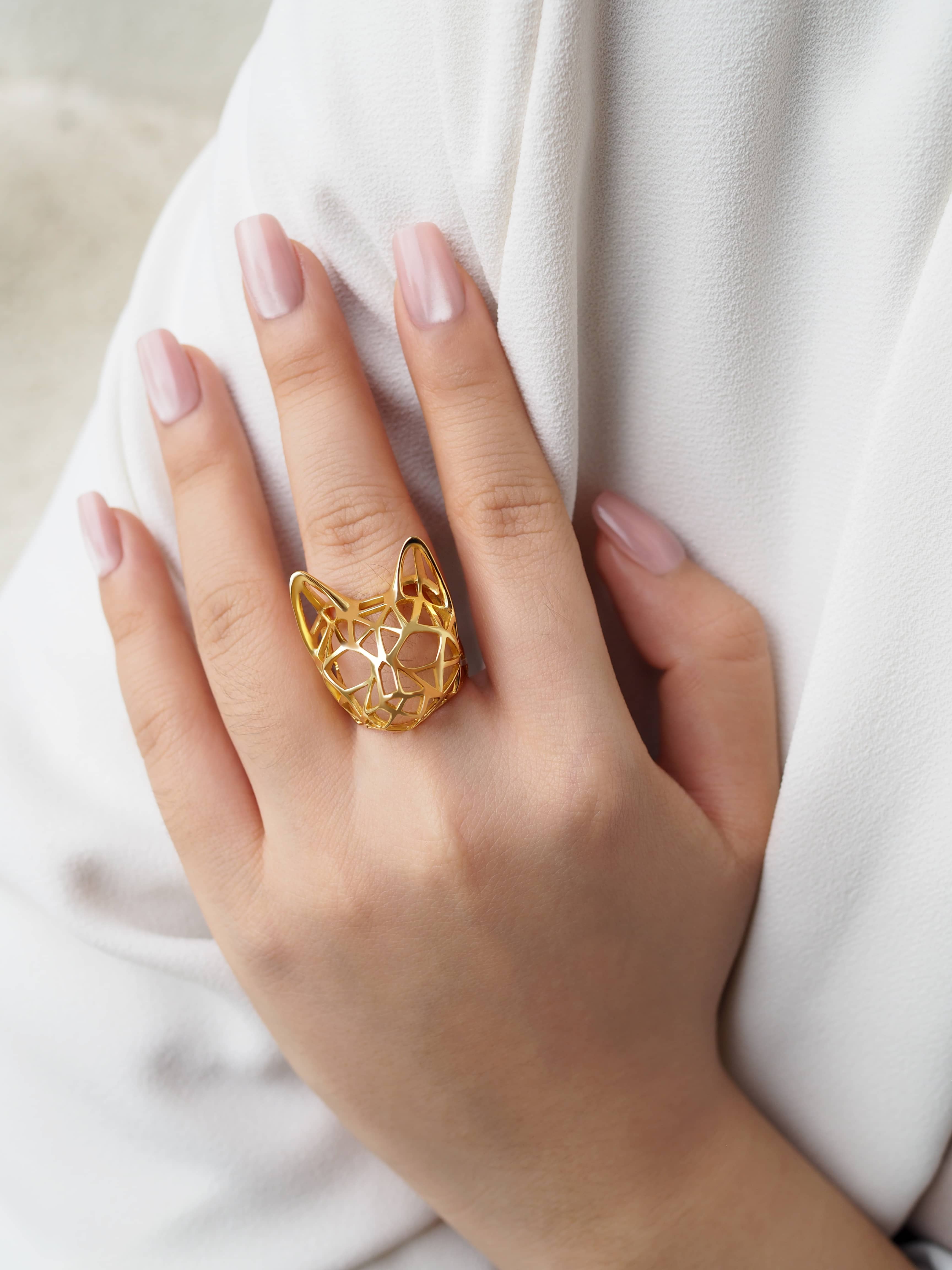 Close-up of a hand adorned with a stylish golden ring designed in the shape of a cat's head.