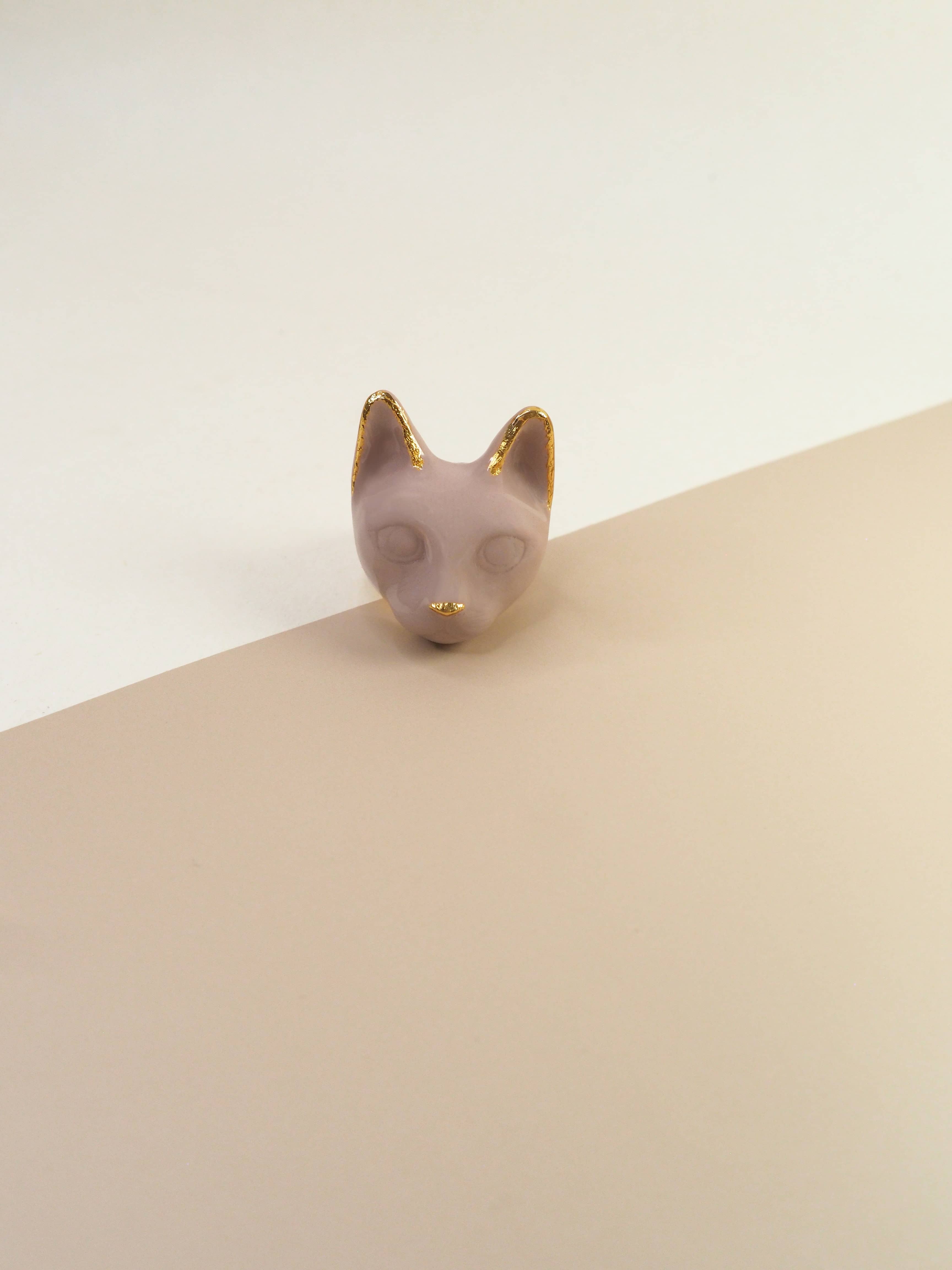 A dusty pink cat's head ring placed on natural color background.