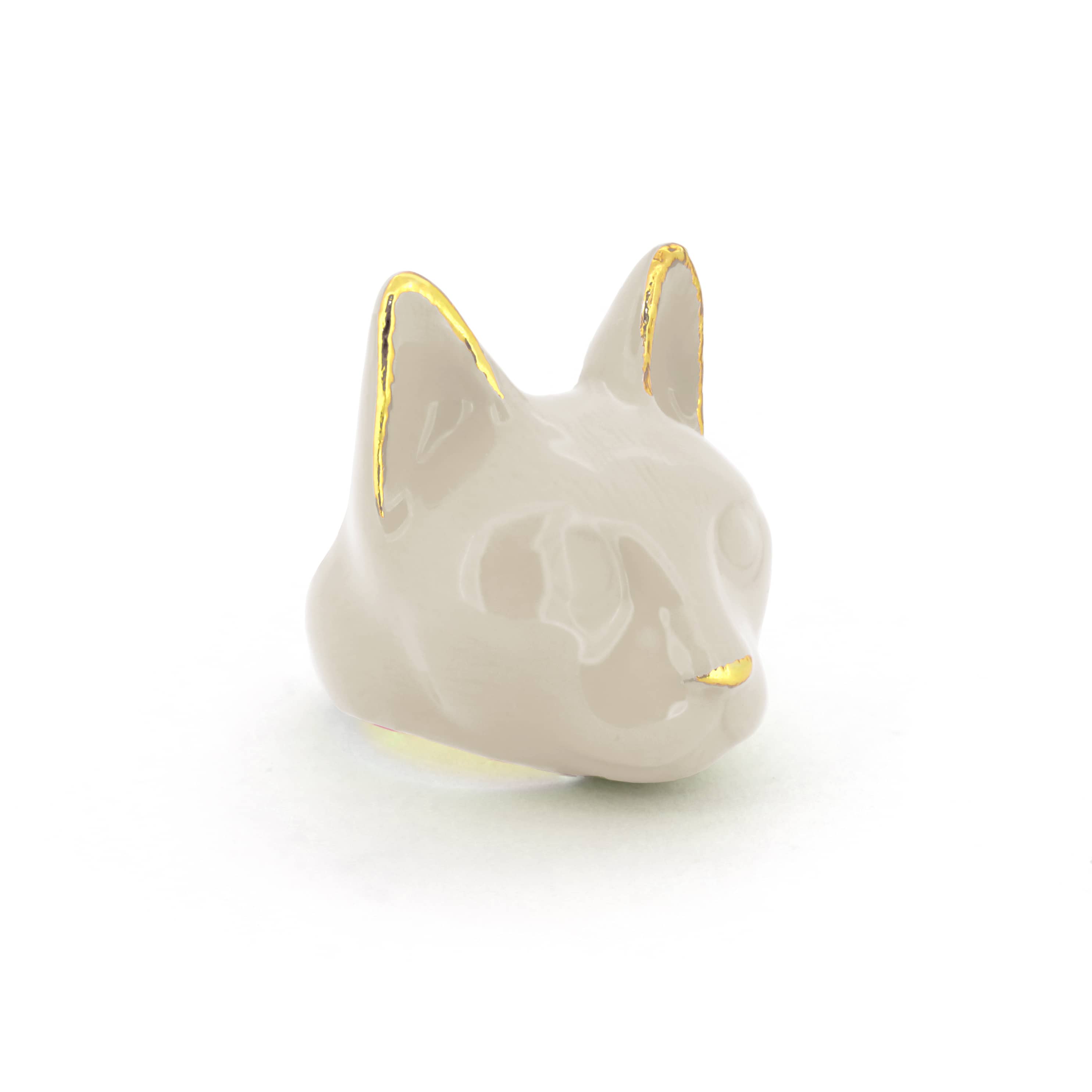 A pale gray cat's head ring with gold accents on the ears and a small gold nose, perfect for art collectors.