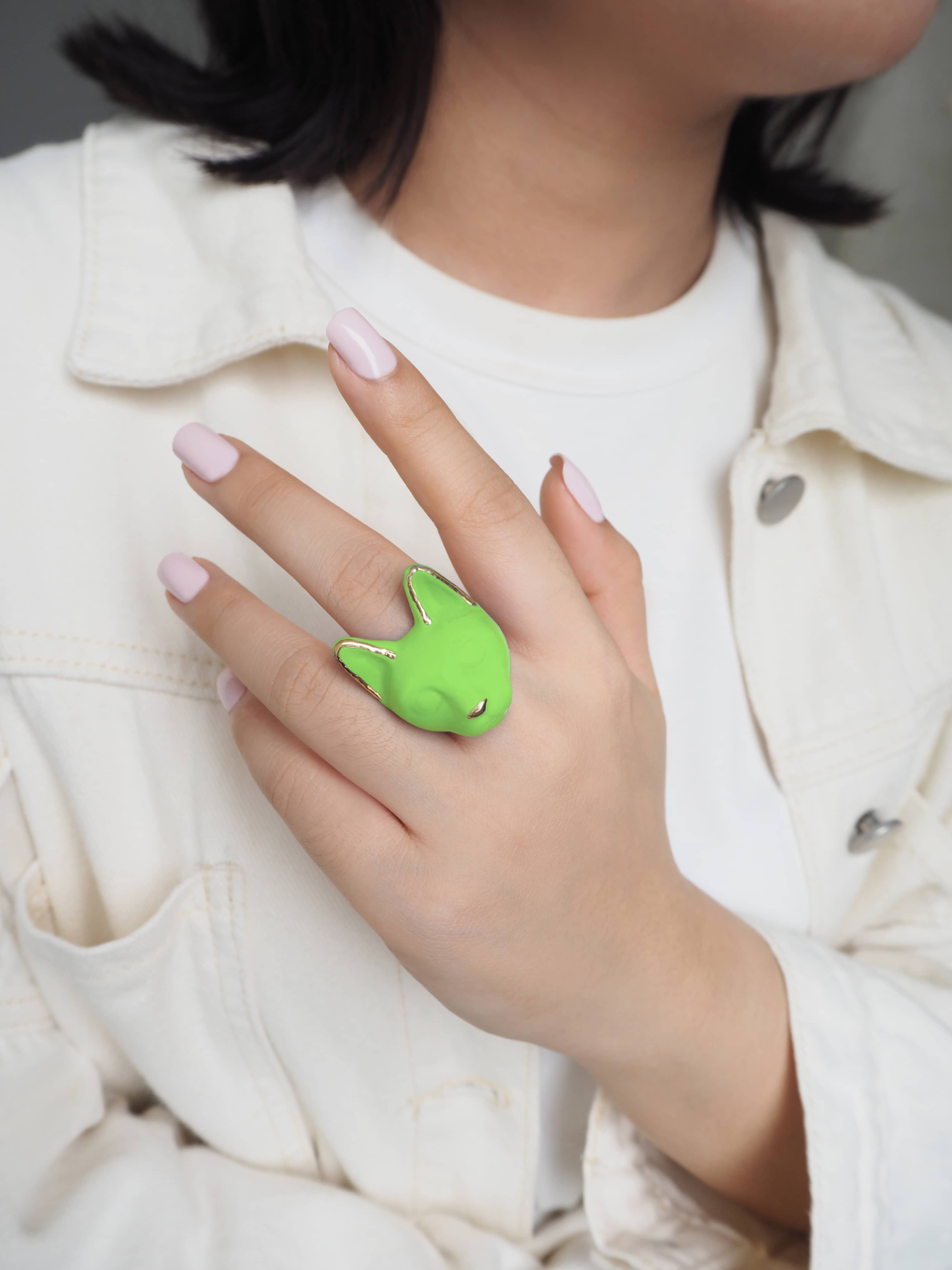Bright green cat-shaped ring worn on a hand with light pink nails.