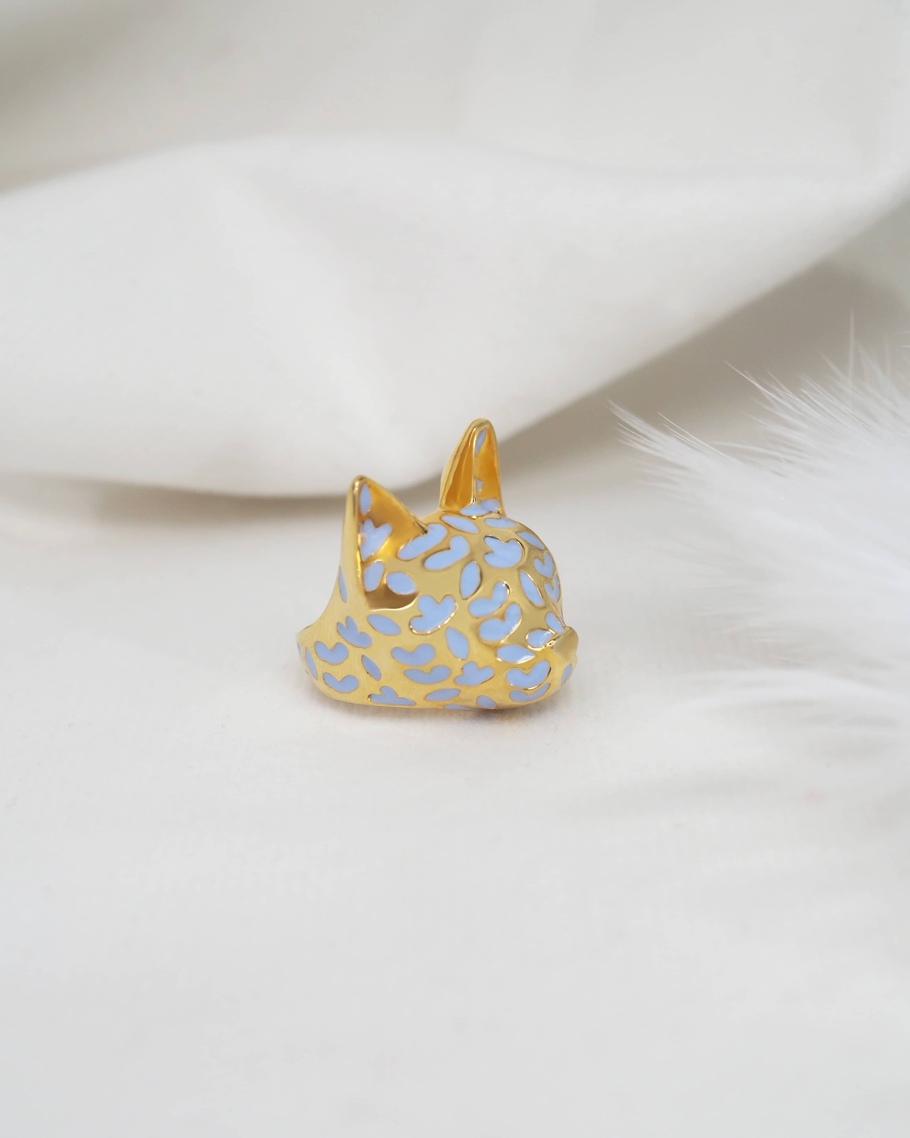 Stunning gold cat ring with lavender-inspired design placed on white fabric.