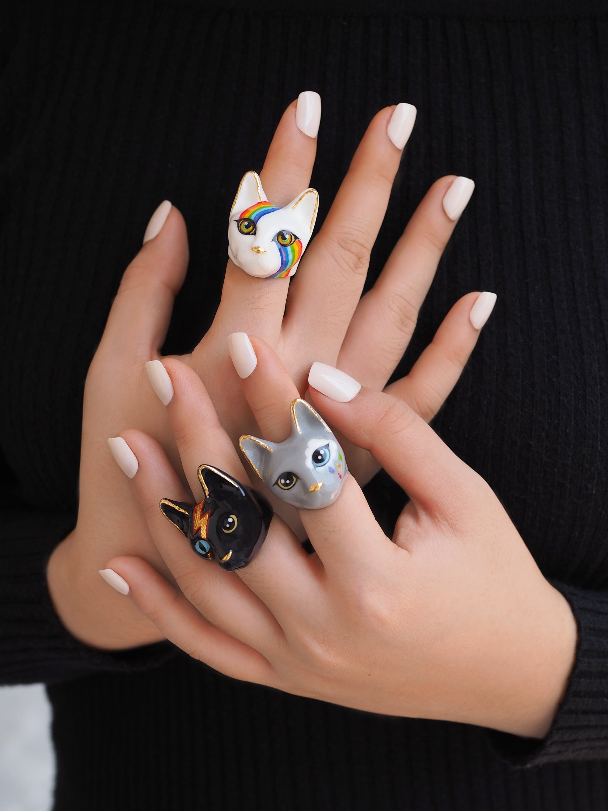 Collection of unique cat rings showcasing designs on fingers.