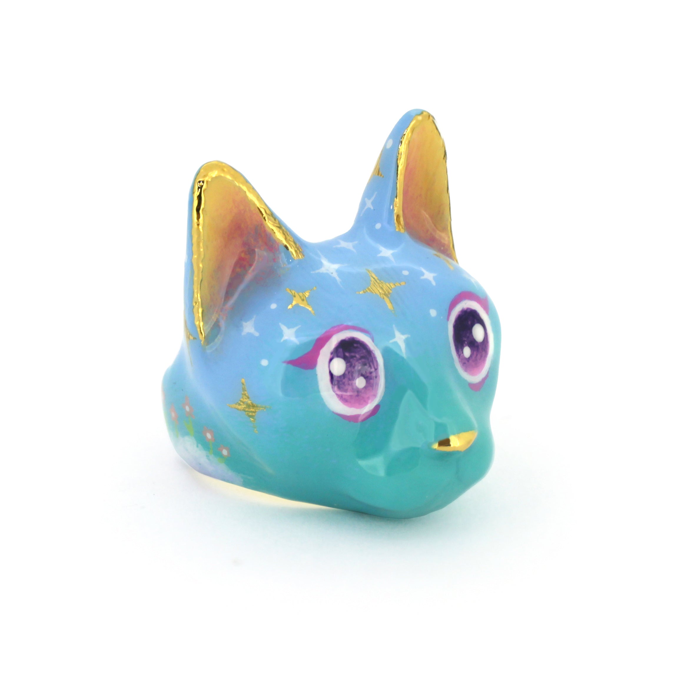 Cat ring in a soft blue color featuring yellow ears and large, sparkling purple eyes and star-like patterns on its forehead, perfect for art collectors.