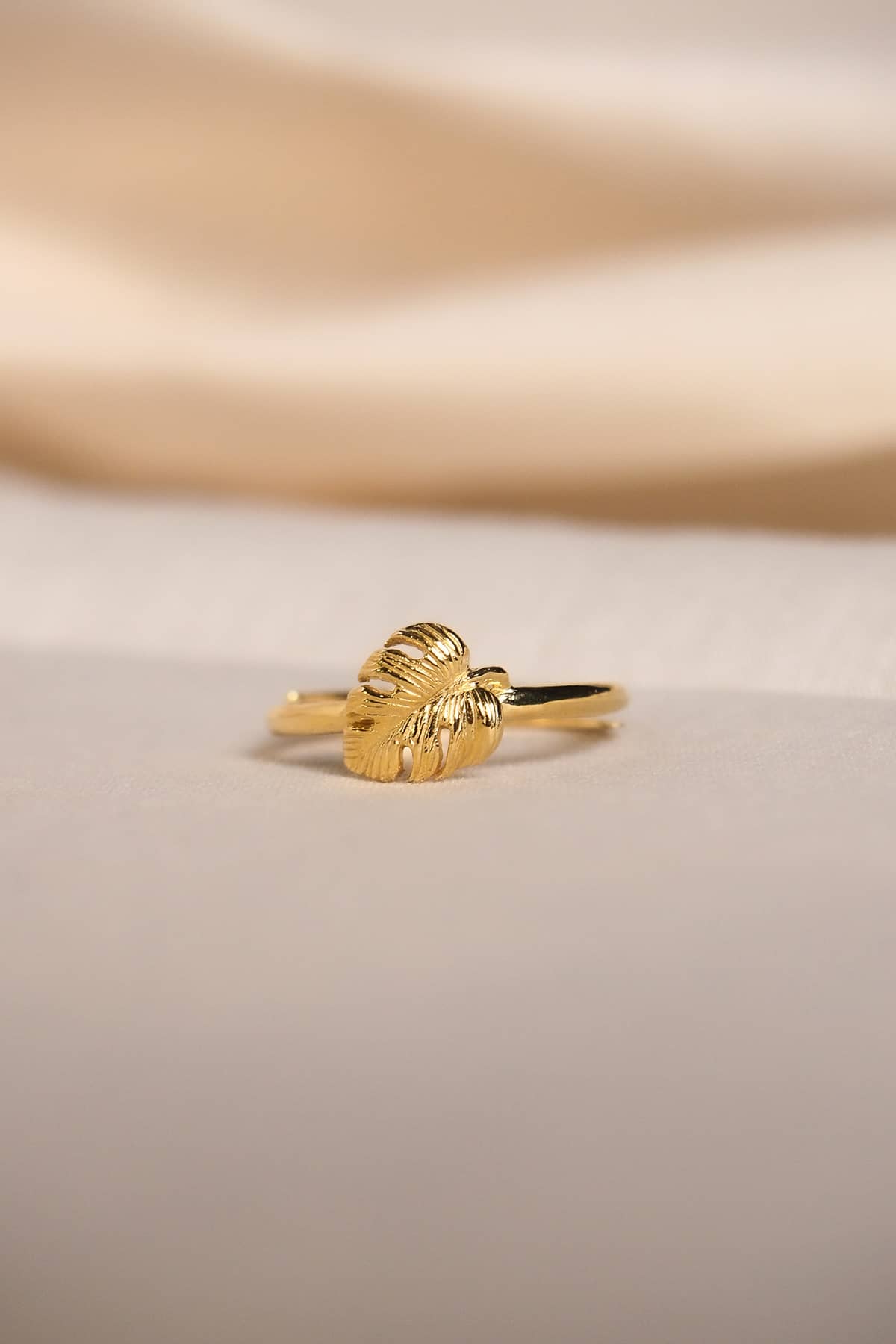 Close-up of delicate gold ring with a leaf design on a soft background