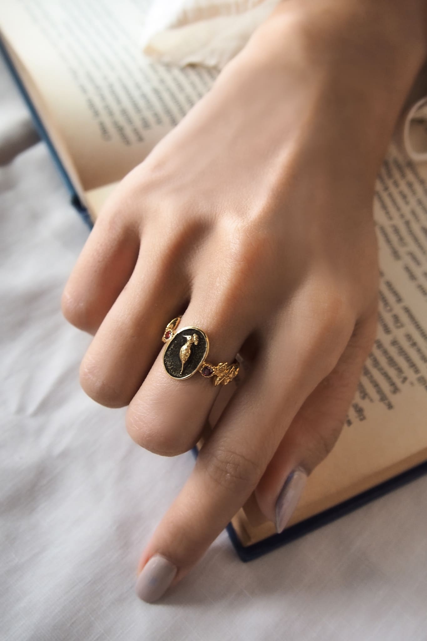 Close-up of a hand wearing an elegant gold ring featuring a hoopoe design.