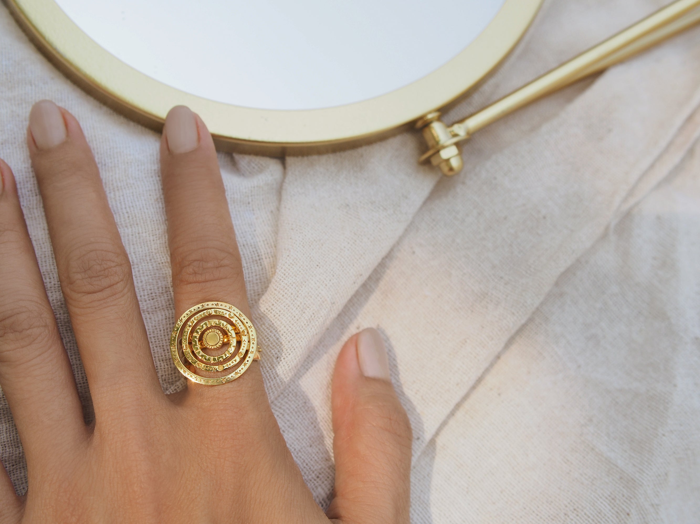 Close-up of a hand adorned with gold star-inspired ring set placed on a fabric.