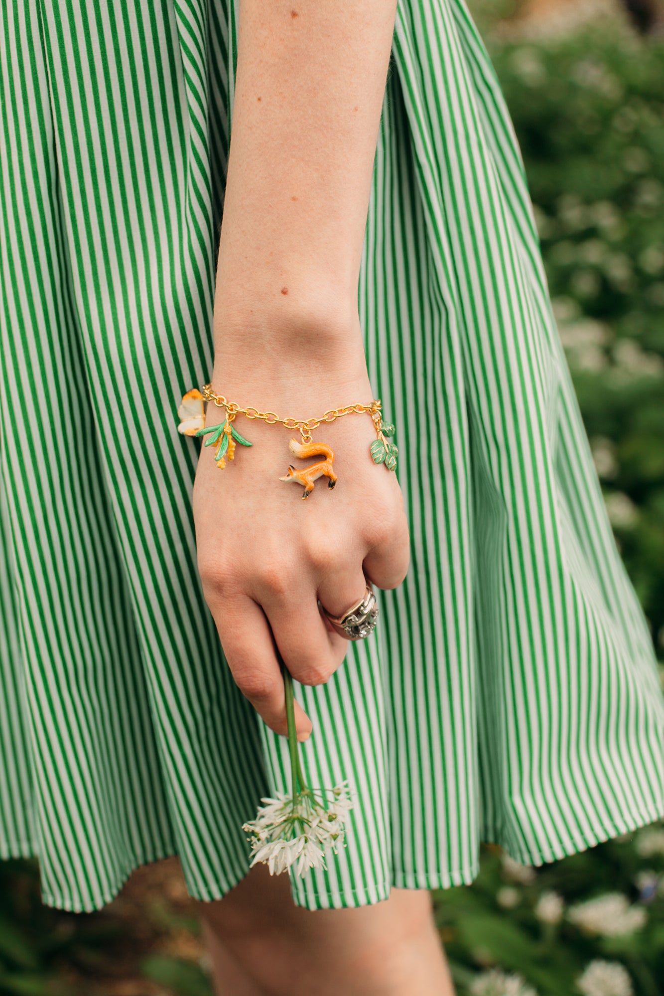 A whimsical gold charm bracelet featuring a fox and butterfly, perfect for nature lovers.