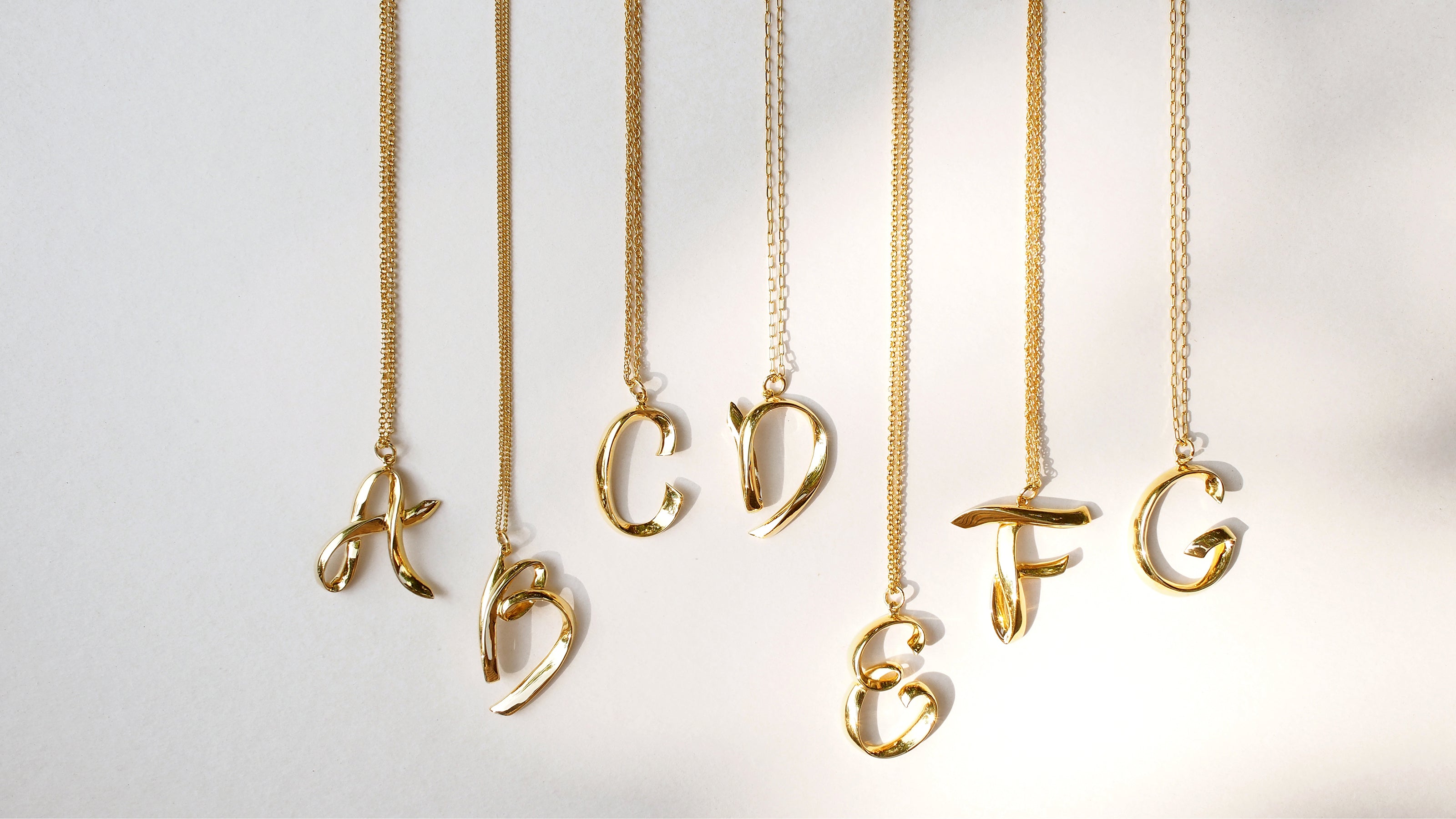 Unique alphabet necklaces in gold plating, showcasing initials A, B, C, D, E, F, and G.