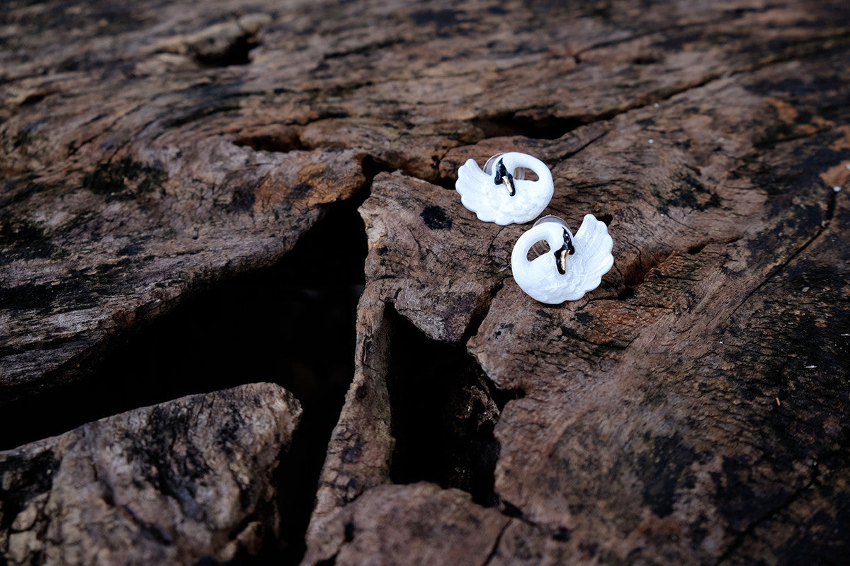 Beautiful swan earrings placed on a wooden surface.