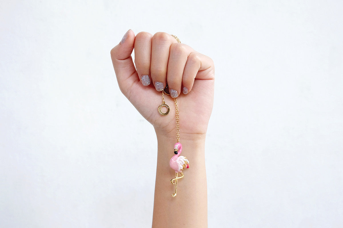 Pink flamingo pendant necklace displayed in a hand with decorative nails.