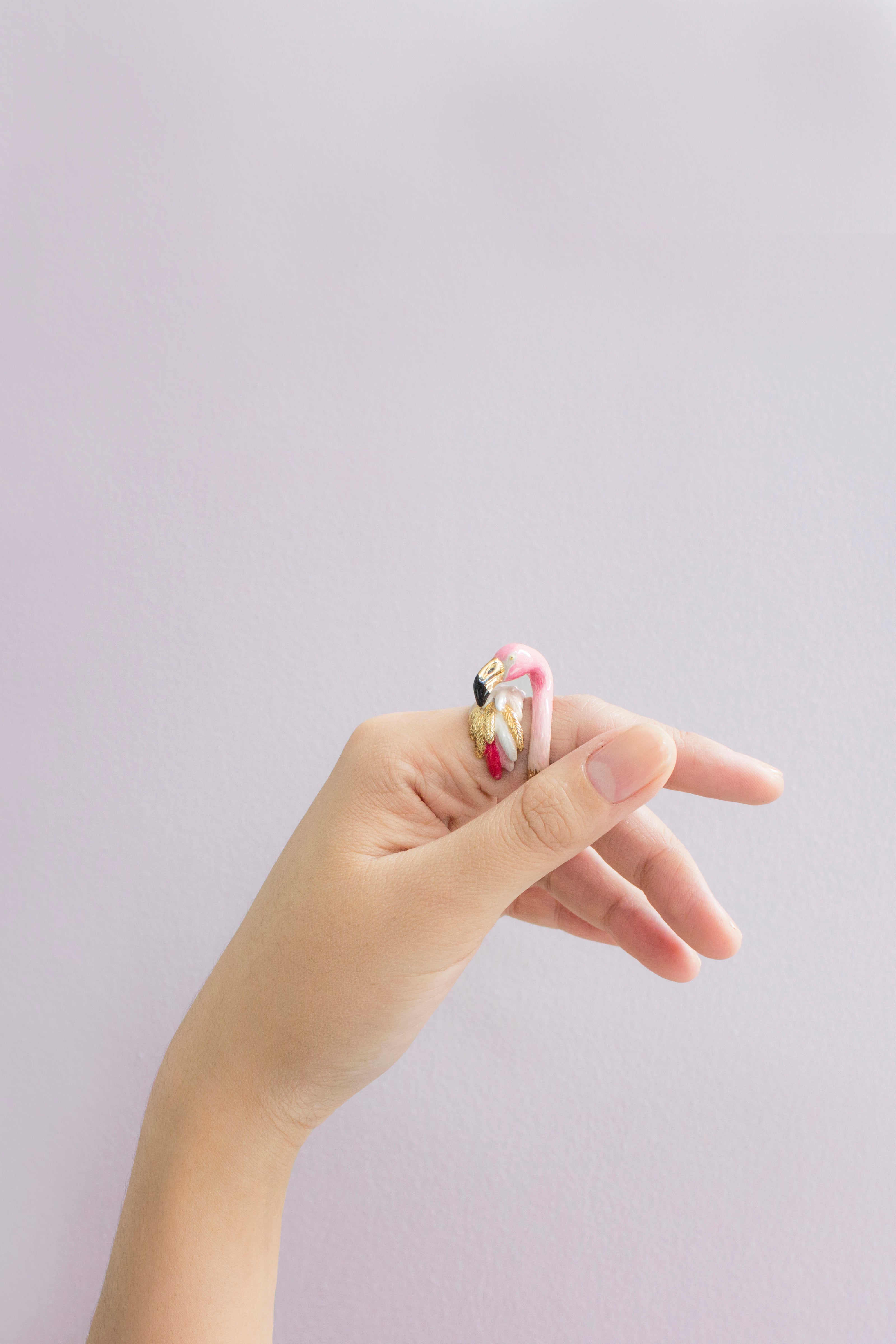 Close-up of a unique flamingo ring worn on a finger.