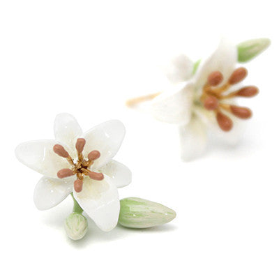 Beautiful handmade flower earrings with white petals and brown stamens, accompanied by green leaves and a budding flower.