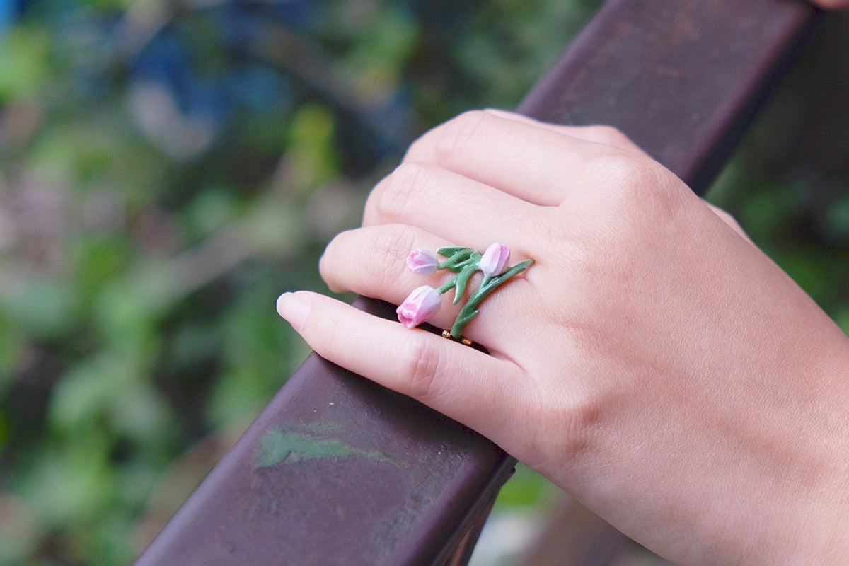 Close-up of a hand wearing a beautiful tulip ring while holding a wooden rail.