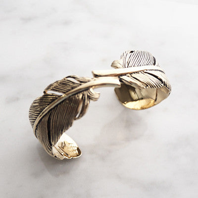Elegant gold bracelet featuring intricate feather design