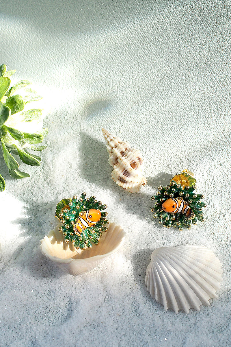 Beautiful ocean-inspired earrings with vibrant clownfish and sea anemone designs surrounded by seashells.
