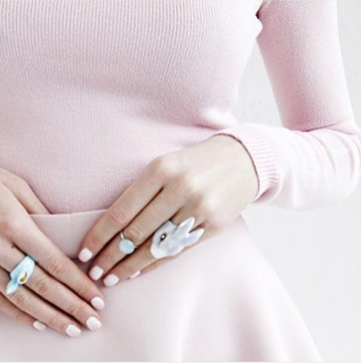 Close-up of hands wearing rabbit ring on a pink sweater.