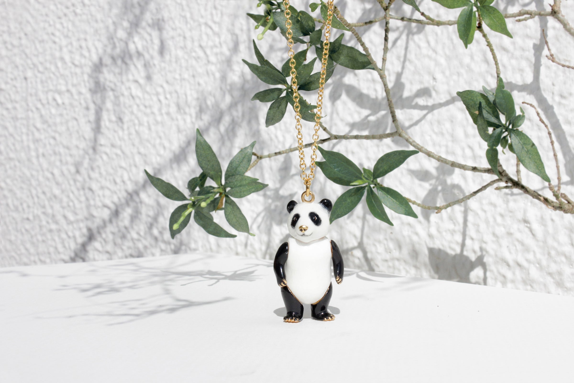 Charming black and white panda pendant necklace placed in the white background with green leaves.