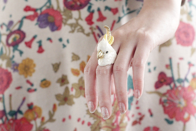 Close-up of a hand showcasing a cockatoo ring with floral dress.