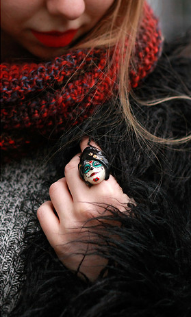 Beautifully crafted sugar skull ring worn on a woman's hand in cozy outfit.