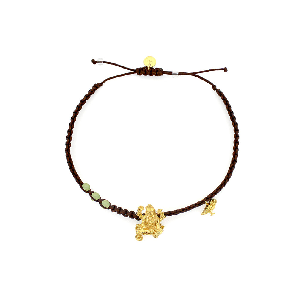 A gold Tridevi Lakshmi charm and a gold owl charm on a brown bracelet with lemon jade stone.