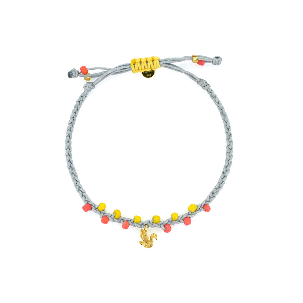 A pastel bracelet in light grey and yellow threads with pastel beads, featuring a gold swan charm.