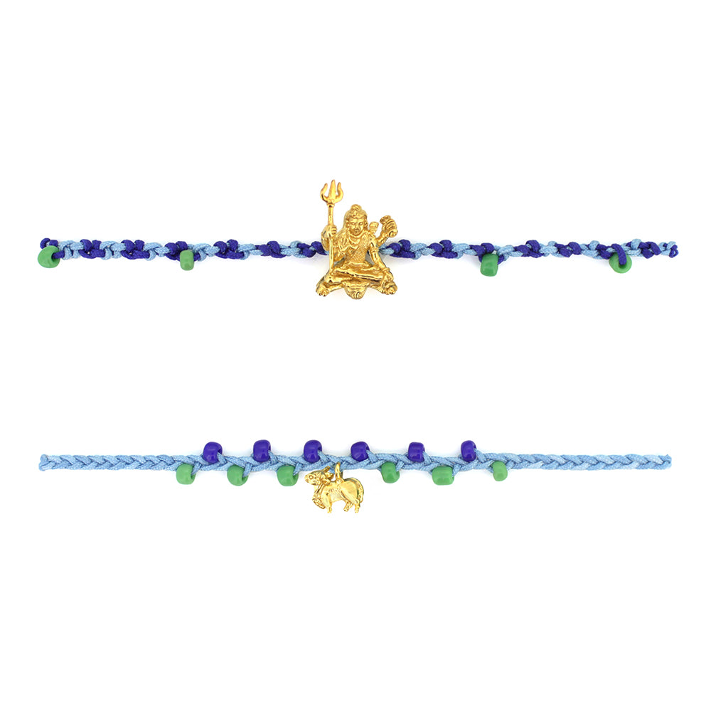 Two colorful bracelets in blue threads with blue and green beads, featuring a gold Trimurti Shiva charm and a gold Nandi charm.