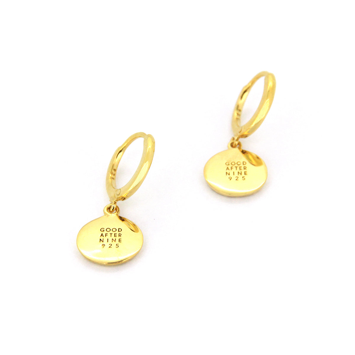Gold drop earrings with circular pendants inscribed with GOOD AFTER NINE logo.