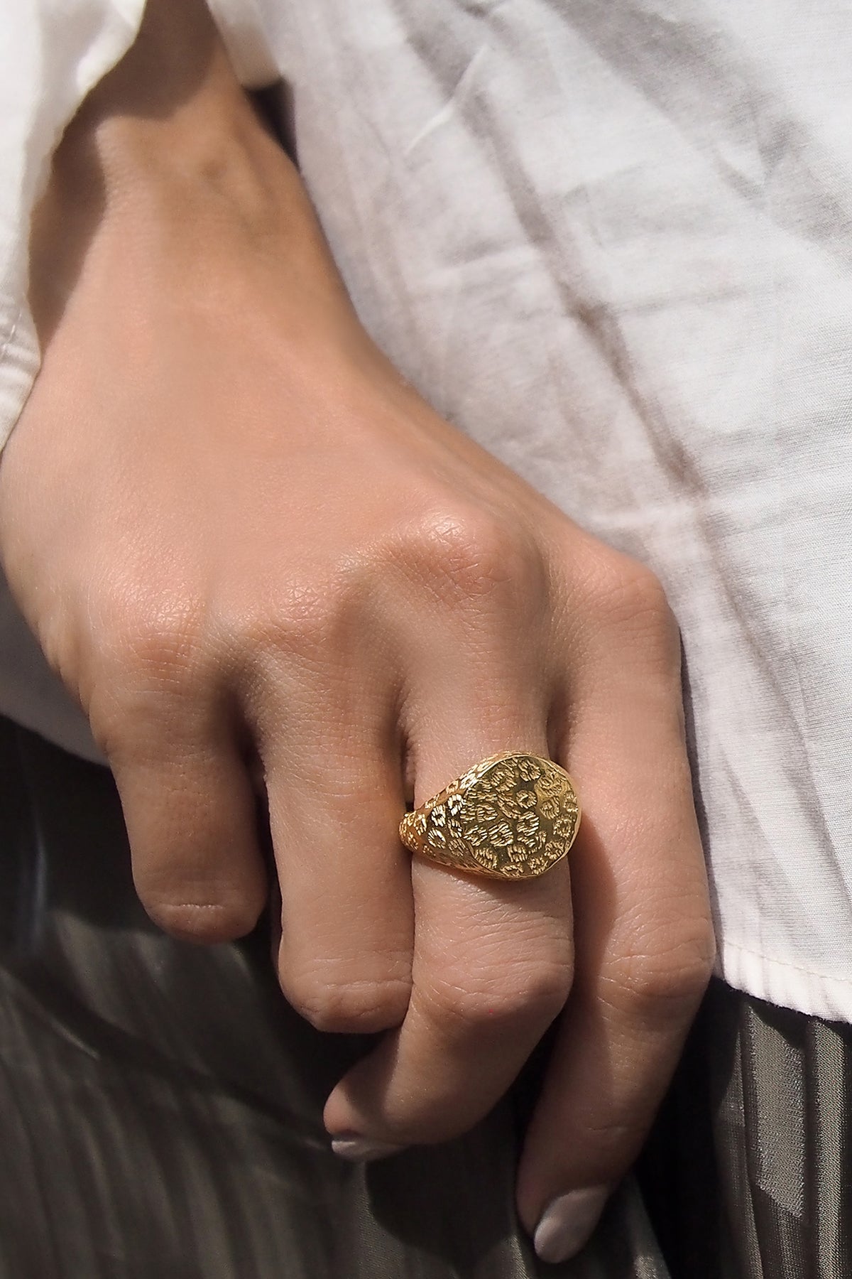 A close-up of a hand adored with gold ring featuring a leopard print.