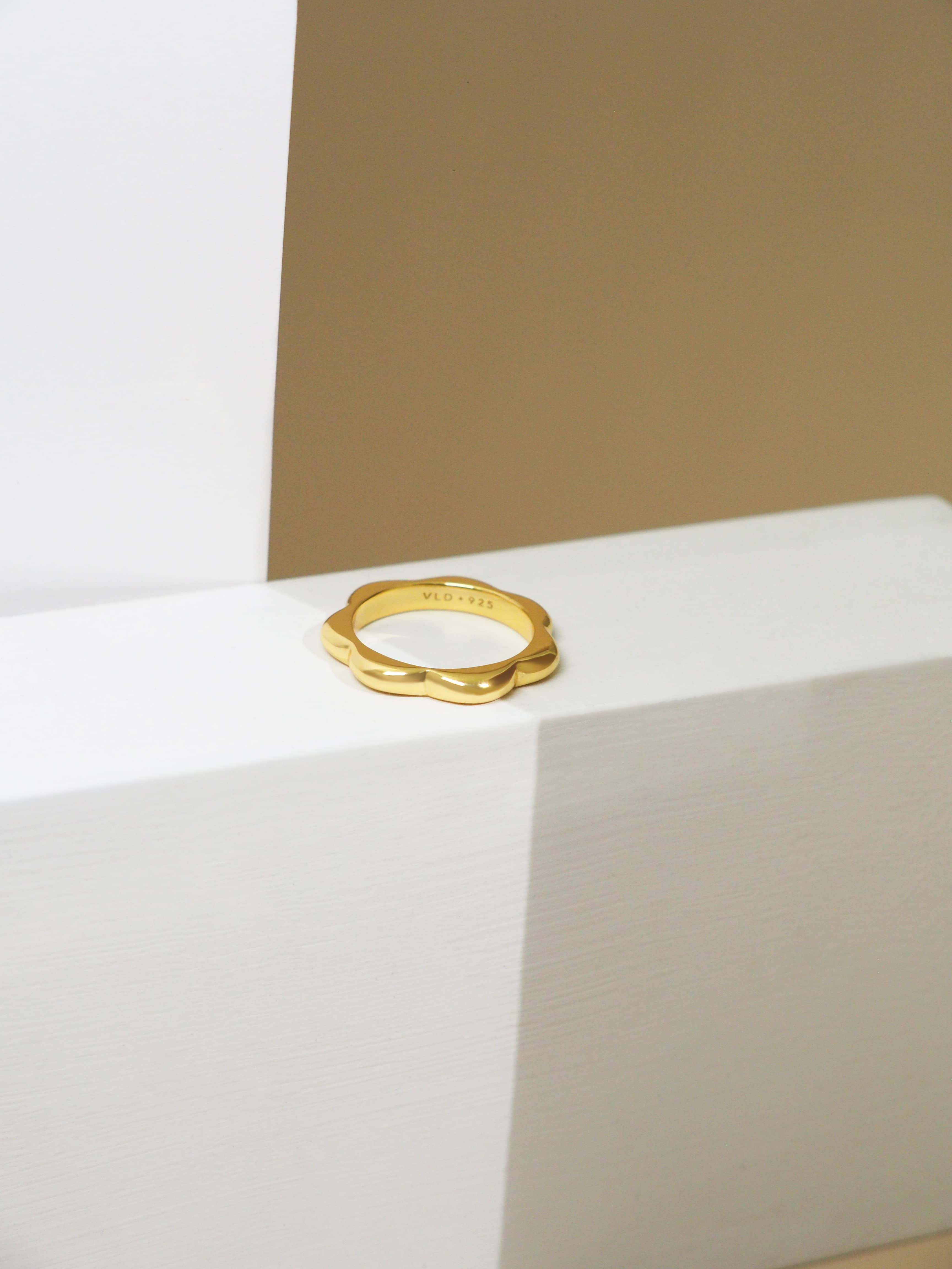 Minimal, bold gold-plated ring ideal for everyday wear lay on the natural-color background.