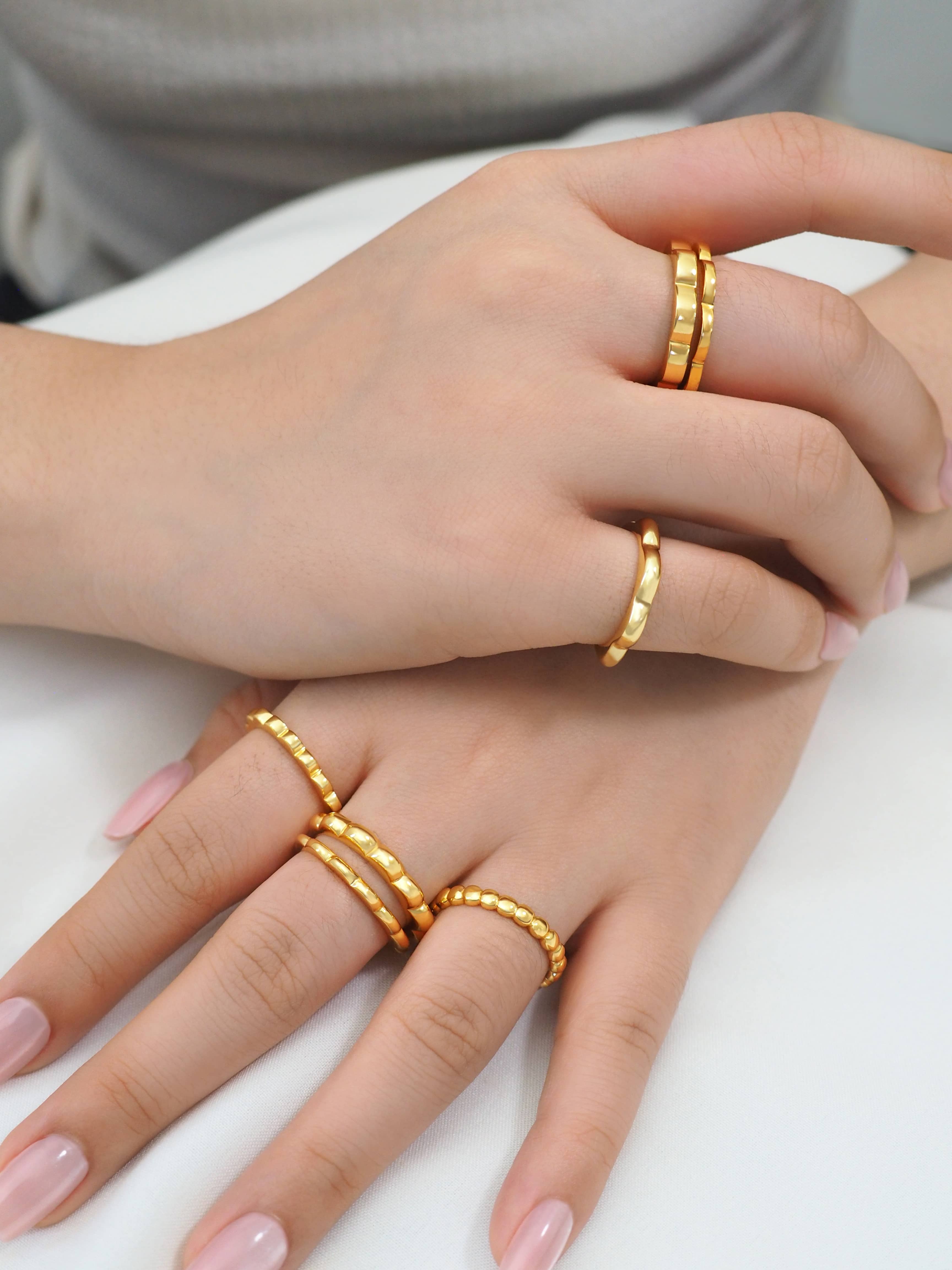 Close-up of hands wearing minimal gold-plated stacking rings