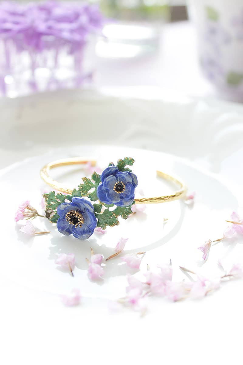 Handcrafted bangle featuring purple flowers and green leaves. Perfect for flower lovers.